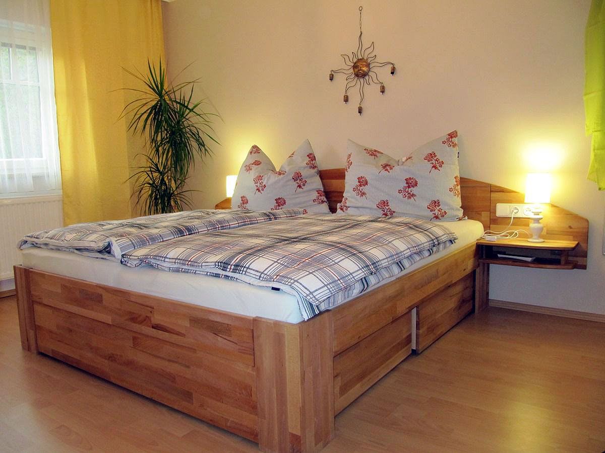 Útulná spálňa s manželskou posteľou, rastlinami a nástennou dekoráciou.