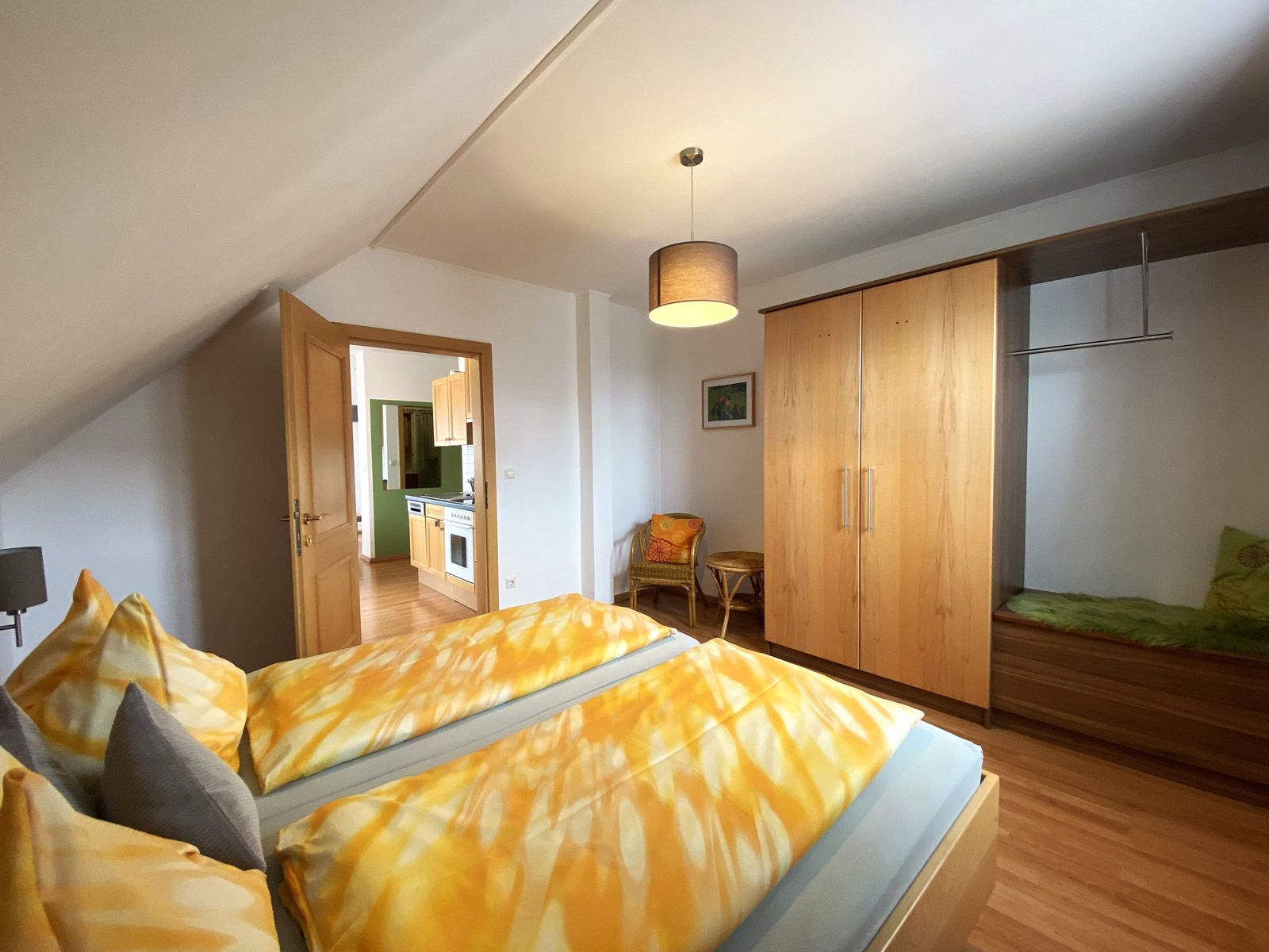 Spálňa s manželskou posteľou, šatníkom a výhľadom do kuchyne.