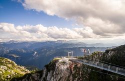 Die majestätischen Berge erheben sich unter einem strahlend blauen Himmel, während sanfte Wolken über die Gipfel ziehen. Wanderer genießen die atemberaubende Aussicht auf die umliegenden Täler und die unberührte Natur, die zu Erkundungen einlädt.