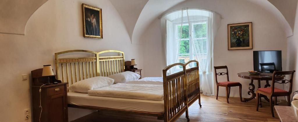 Útulná izba pre hostí s manželskou posteľou, dreveným nábytkom a veľkým oknom so závesmi.