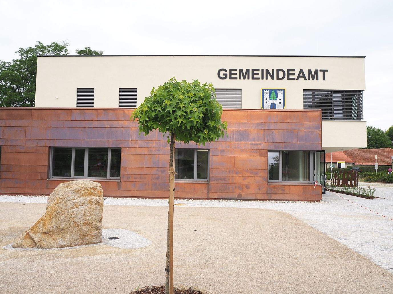 Moderná budova obecného úradu v Sieghartskirchene so stromom a kameňom v popredí.