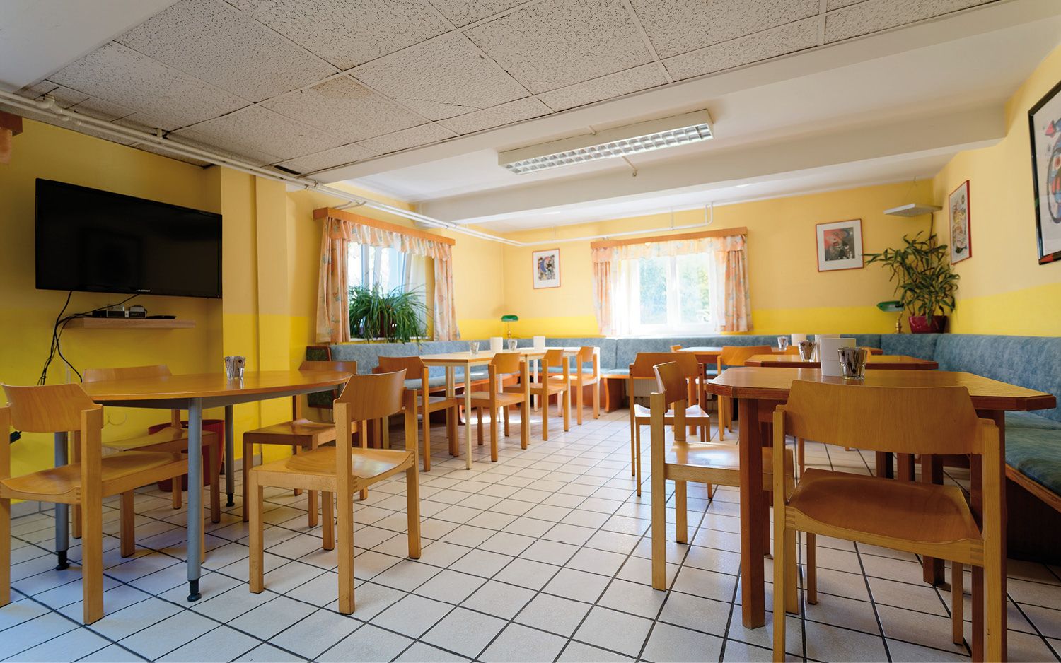 Svetlá raňajková miestnosť s dreveným nábytkom, žltými stenami a veľkými oknami.
