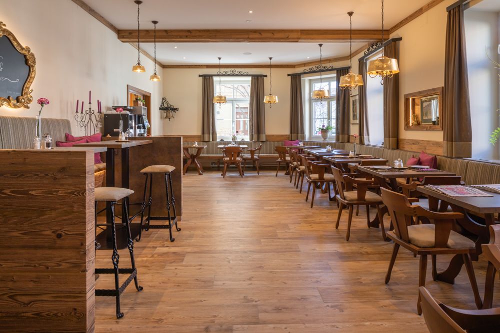 Útulný raňajkový kút s dreveným nábytkom a veľkými oknami.