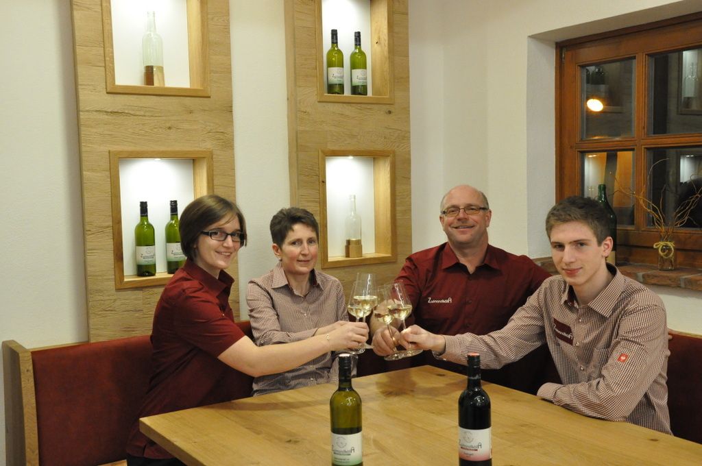 Štyria ľudia si pri stole cinknú pohárom vína.