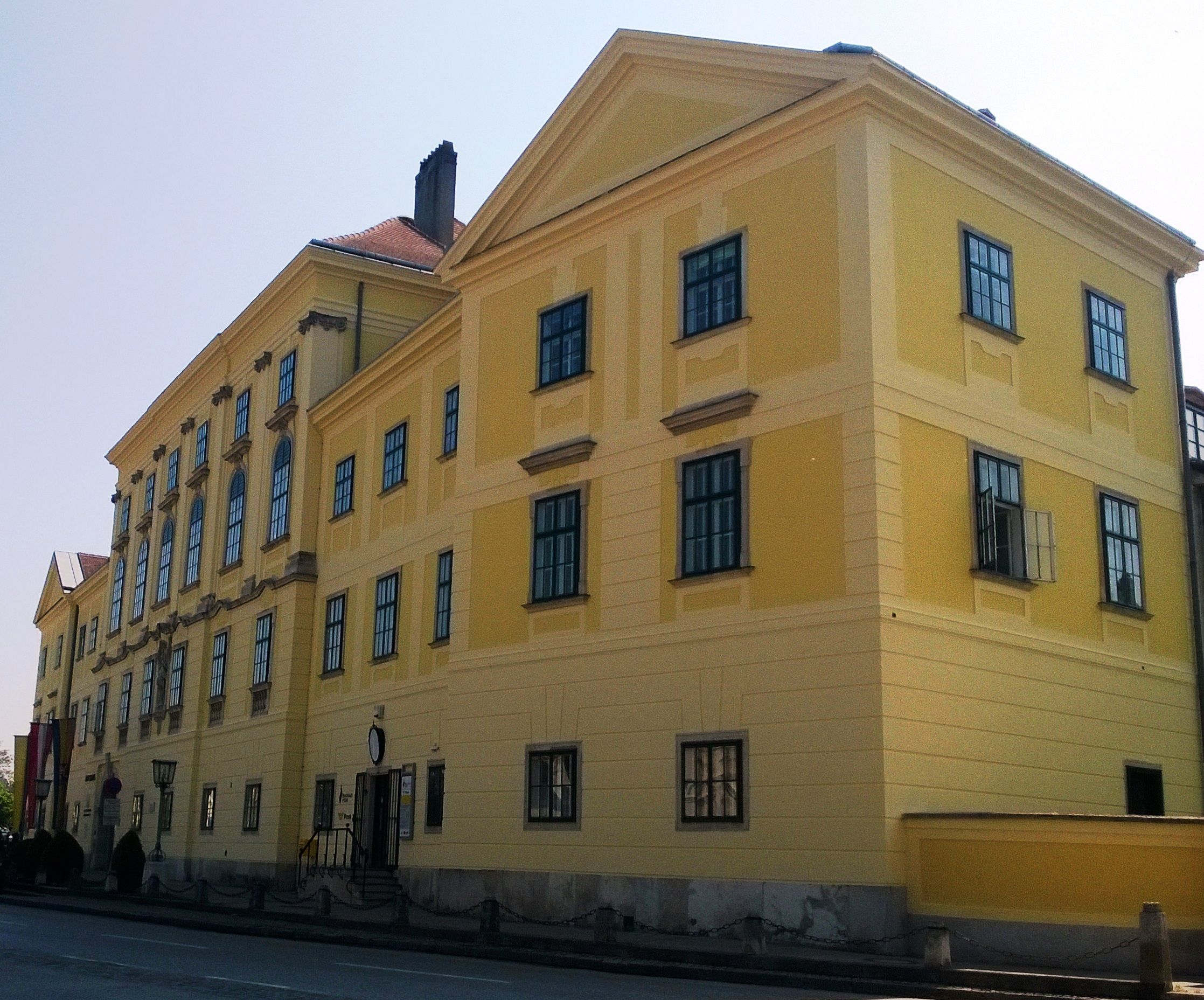 Žltá historická budova s množstvom okien a sedlovou strechou.