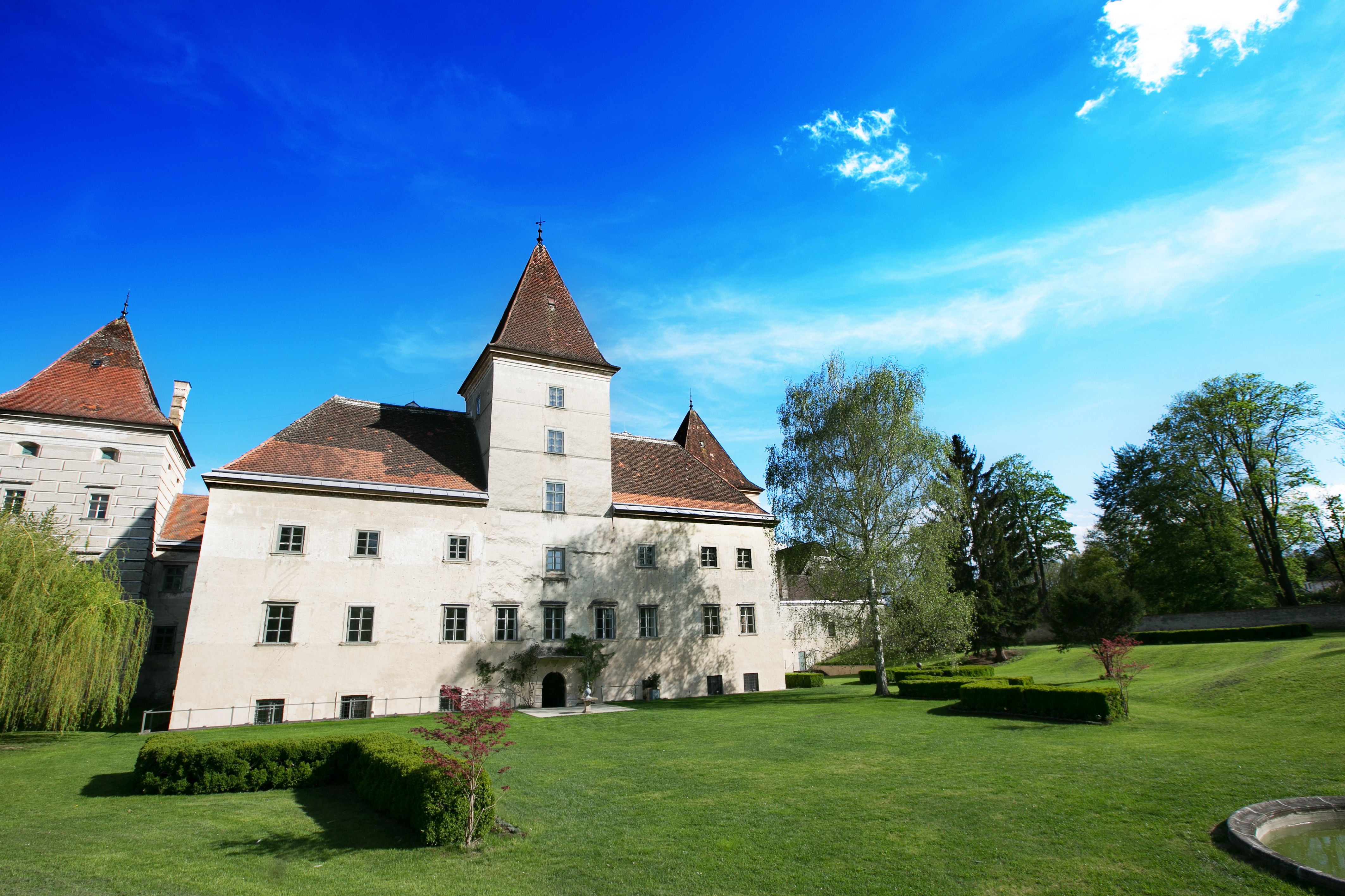 Zámok Walpersdorf so záhradou a modrou oblohou.