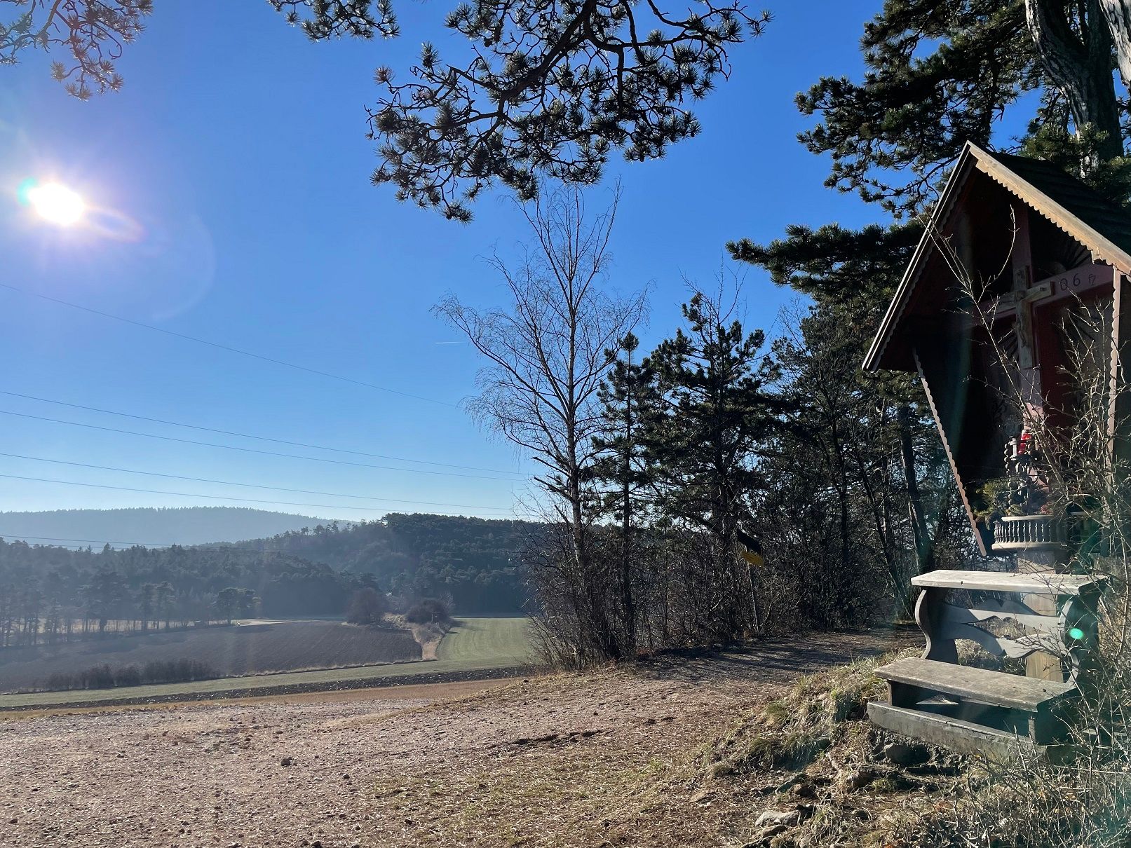 Krajina s chatou a stromami na slnku.