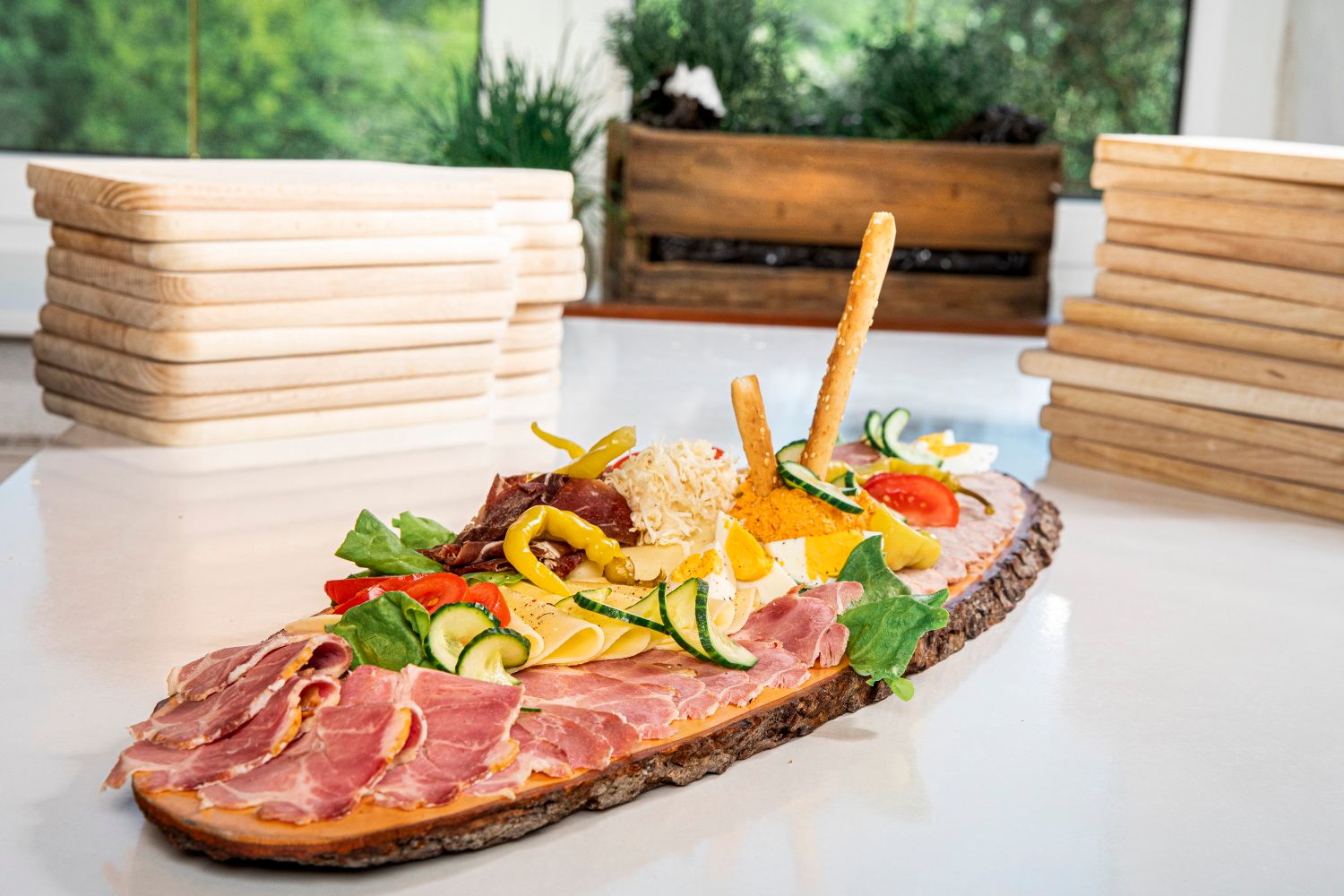 Heurigen tanier so šunkou, syrom, zeleninou a tyčinkami na drevenej rustikálnej doske.