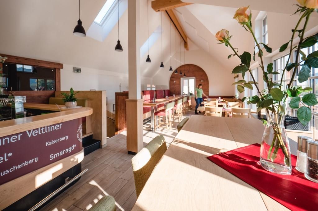 Pohľad do interiéru modernej Viechy s dreveným nábytkom a veľkými oknami.