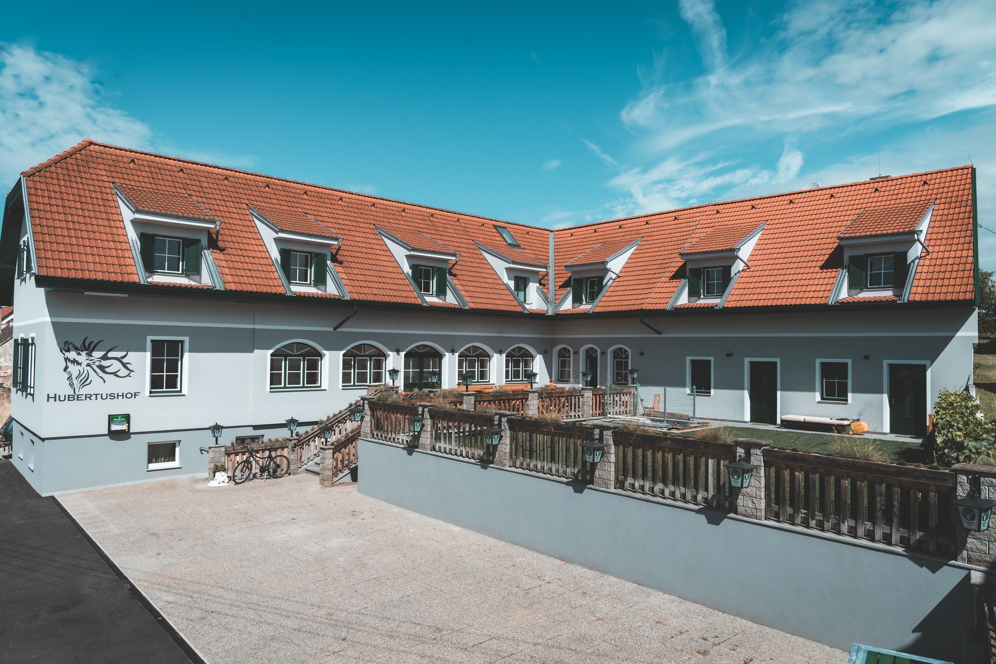 Budova s červenými škridlami a niekoľkými strešnými oknami, označená ako "Hubertushof".