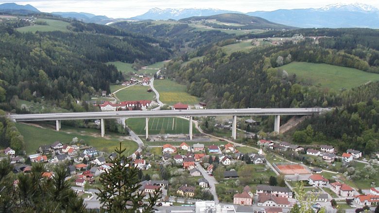 Panoramatický pohľad na obec Warth s mostom a okolitými kopcami.