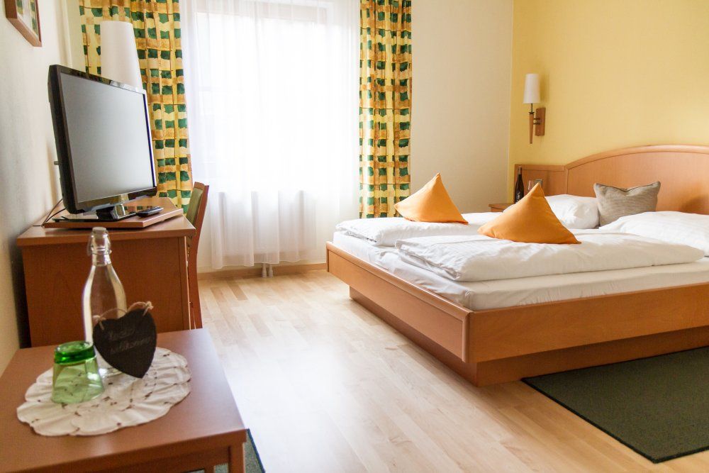 Útulná hotelová izba s manželskou posteľou, TV a závesmi.