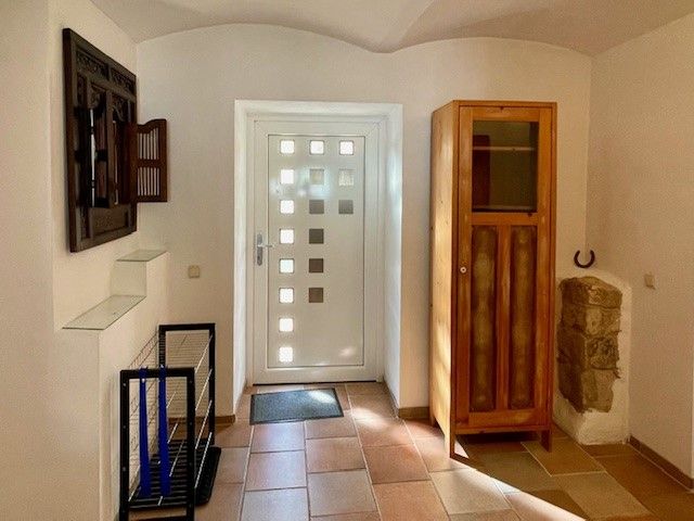 Vstupný priestor s bielymi dverami, drevenou skriňou a dláždenou podlahou.