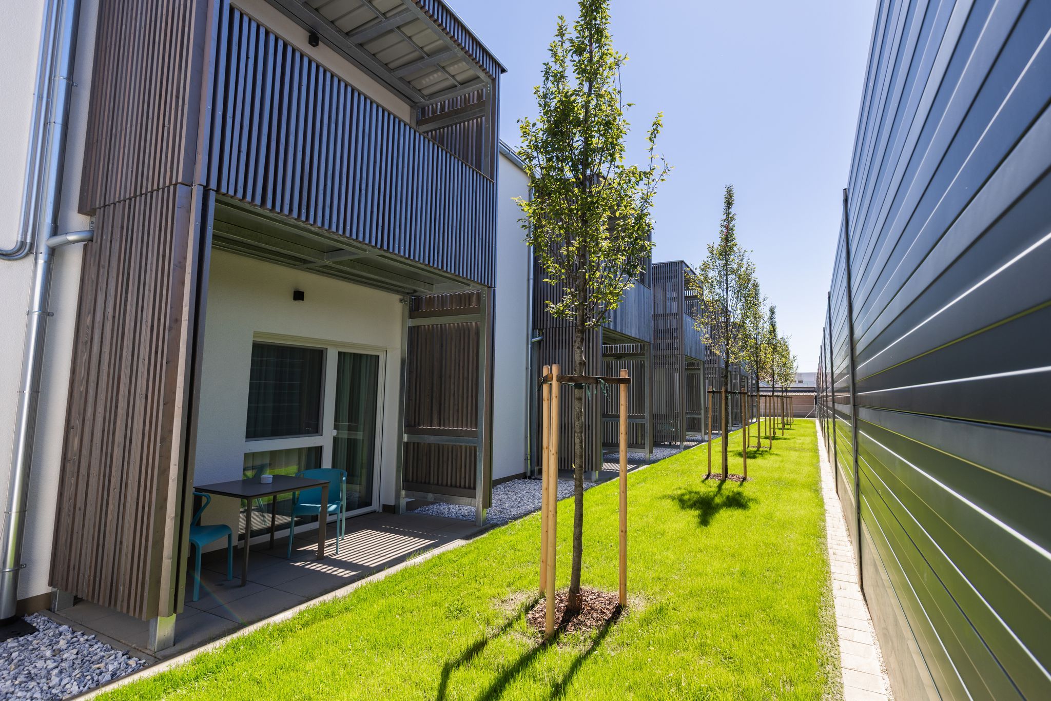 Moderný bytový komplex s balkónmi a udržiavaným trávnikom.