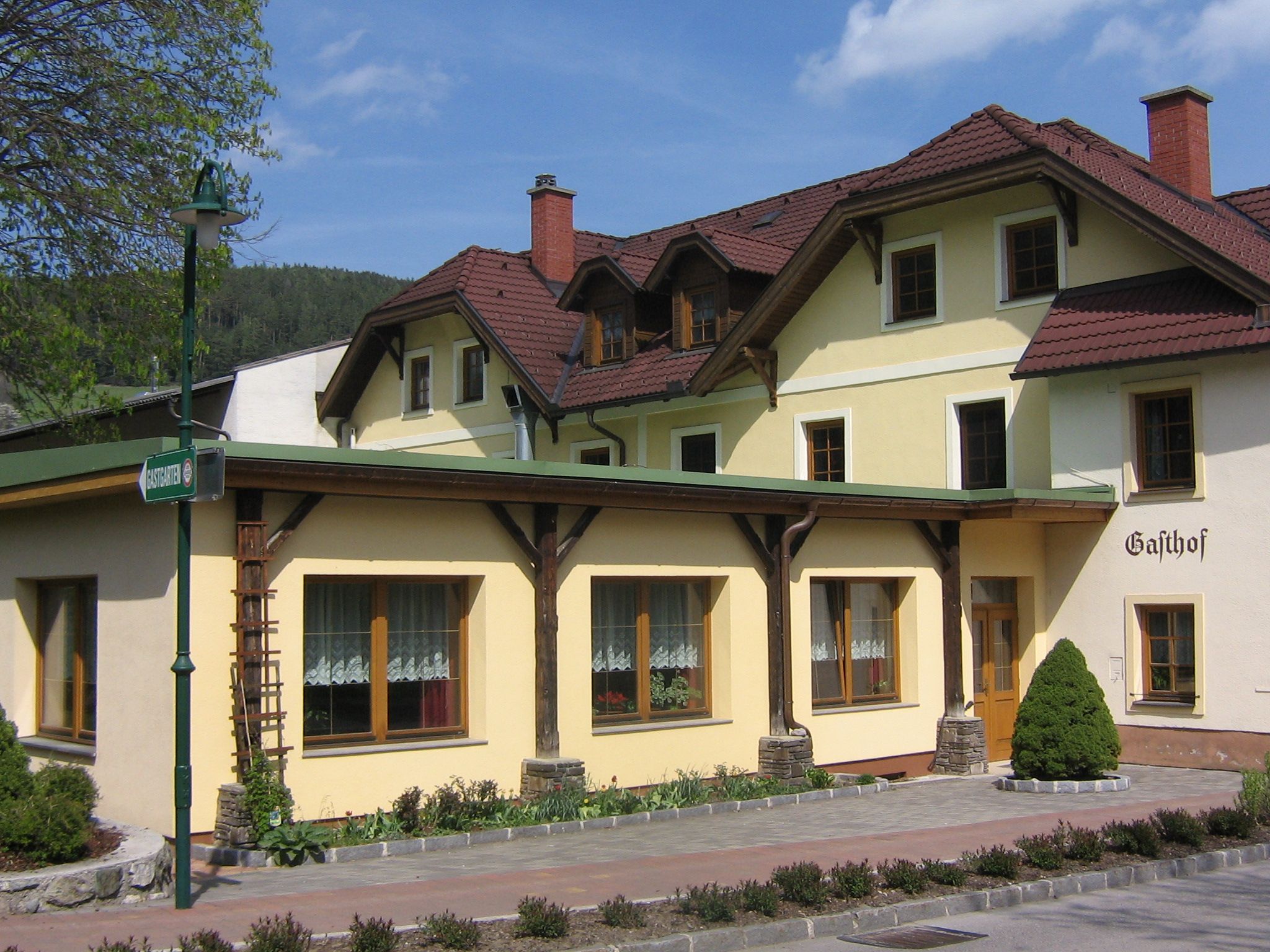 Tradičný hostinec so žltou fasádou a červenými škridlami na streche.