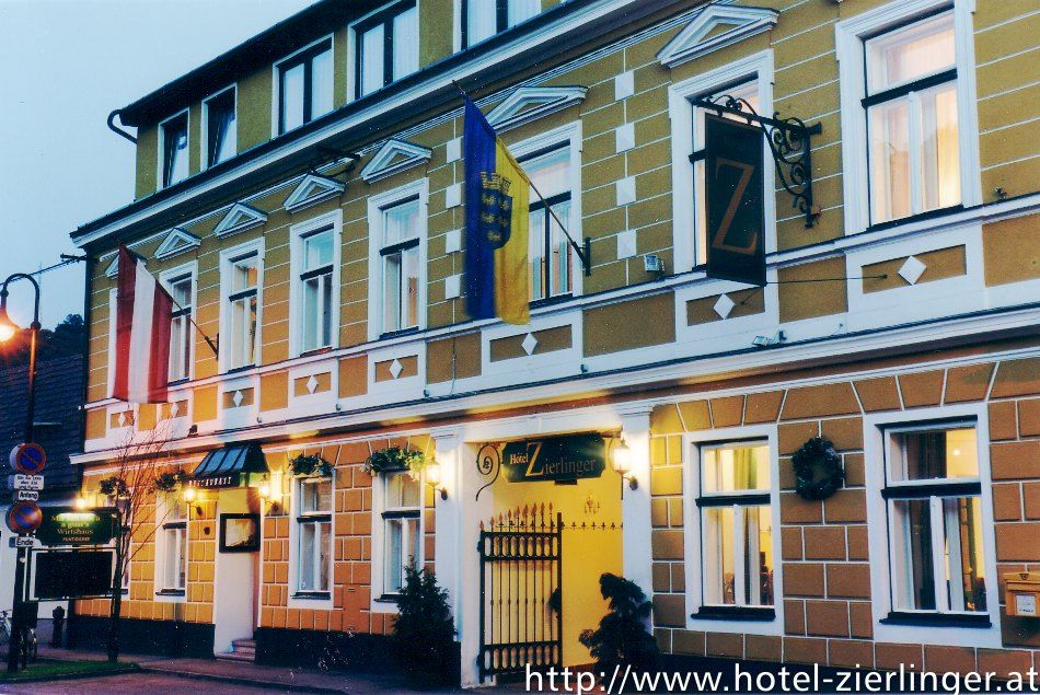 Exteriérový pohľad na hotel Zierlinger so žltou fasádou a vlajkami.