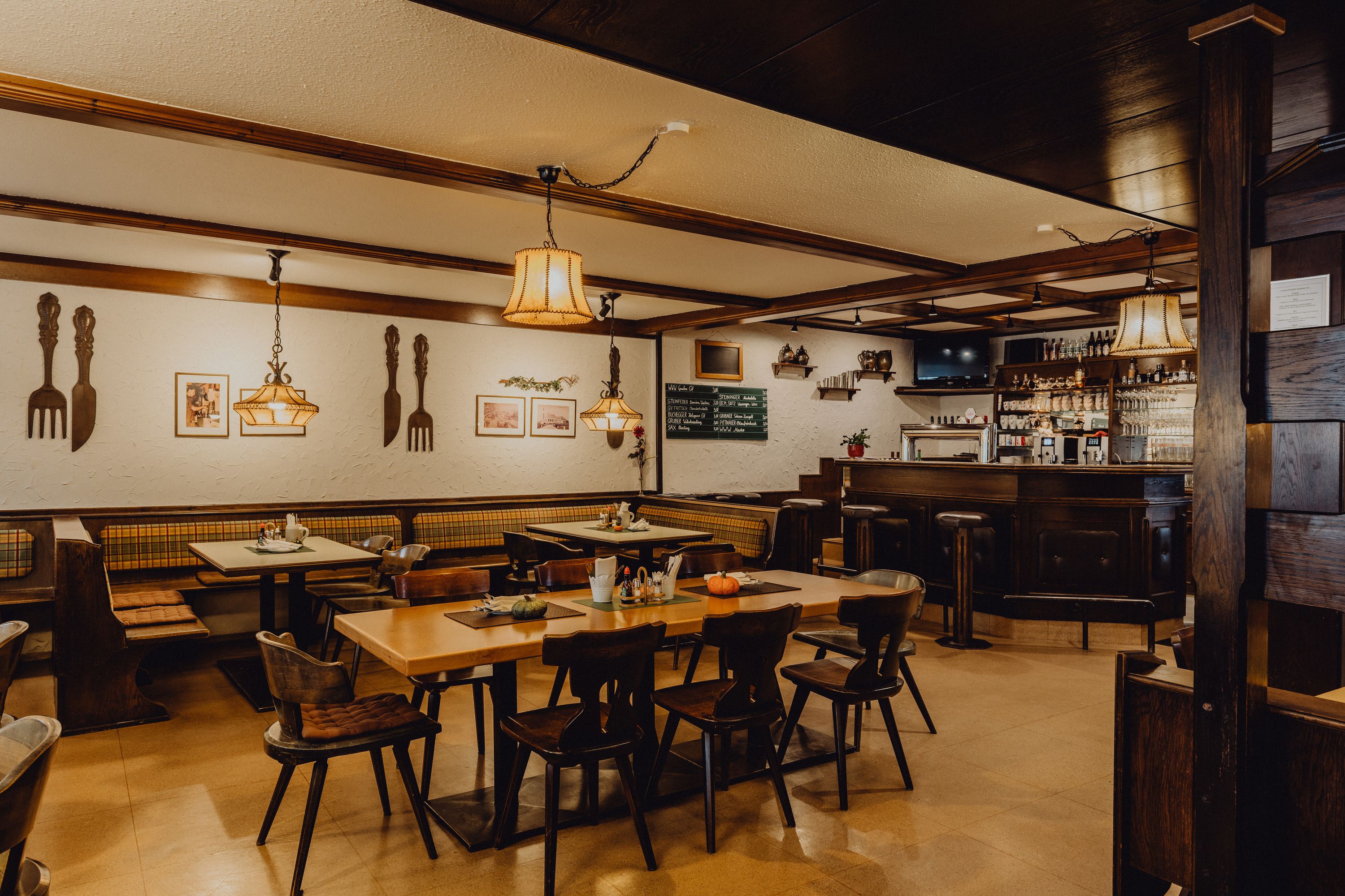 Útulná krčma s dreveným nábytkom, barovým pultom a ozdobnými lampami.