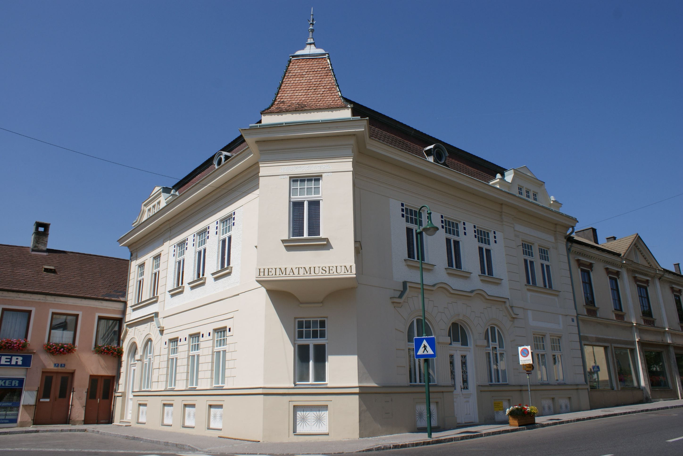 Historická budova s označením "Heimatmuseum" v rakúskom meste Mank pod jasnou oblohou.