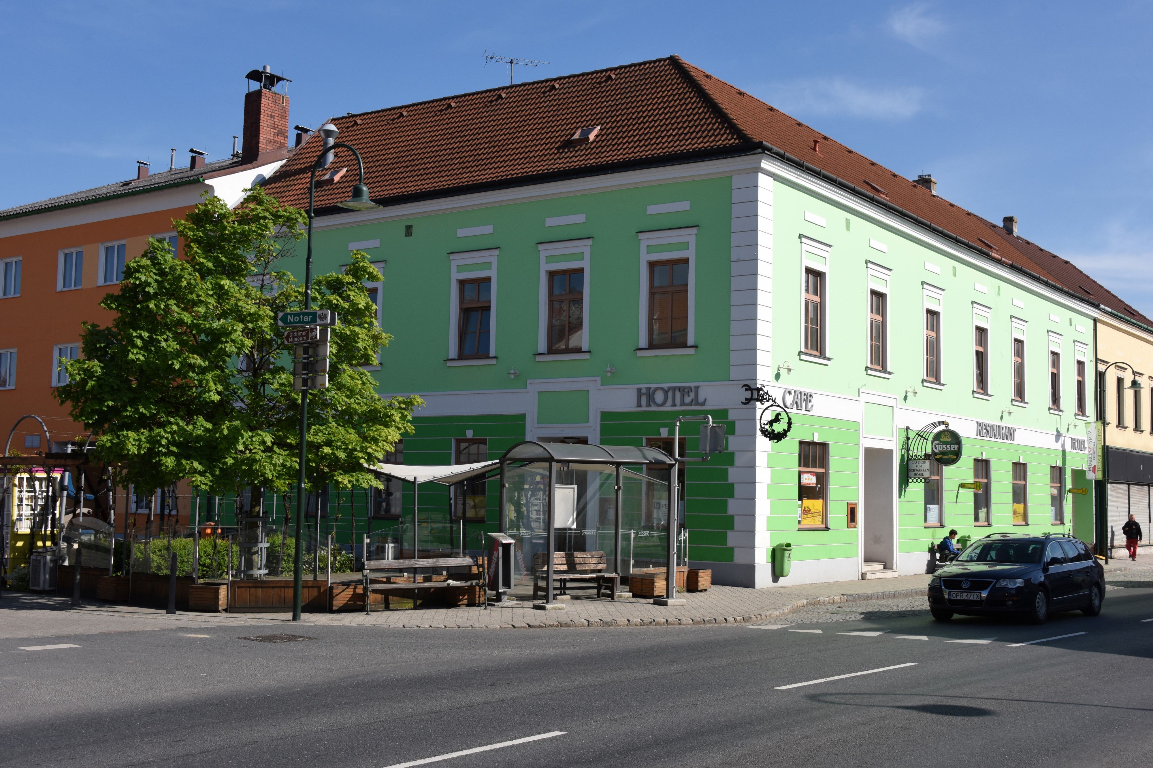 Zelená budova s nápismi hotel a kaviareň na rohu ulice.