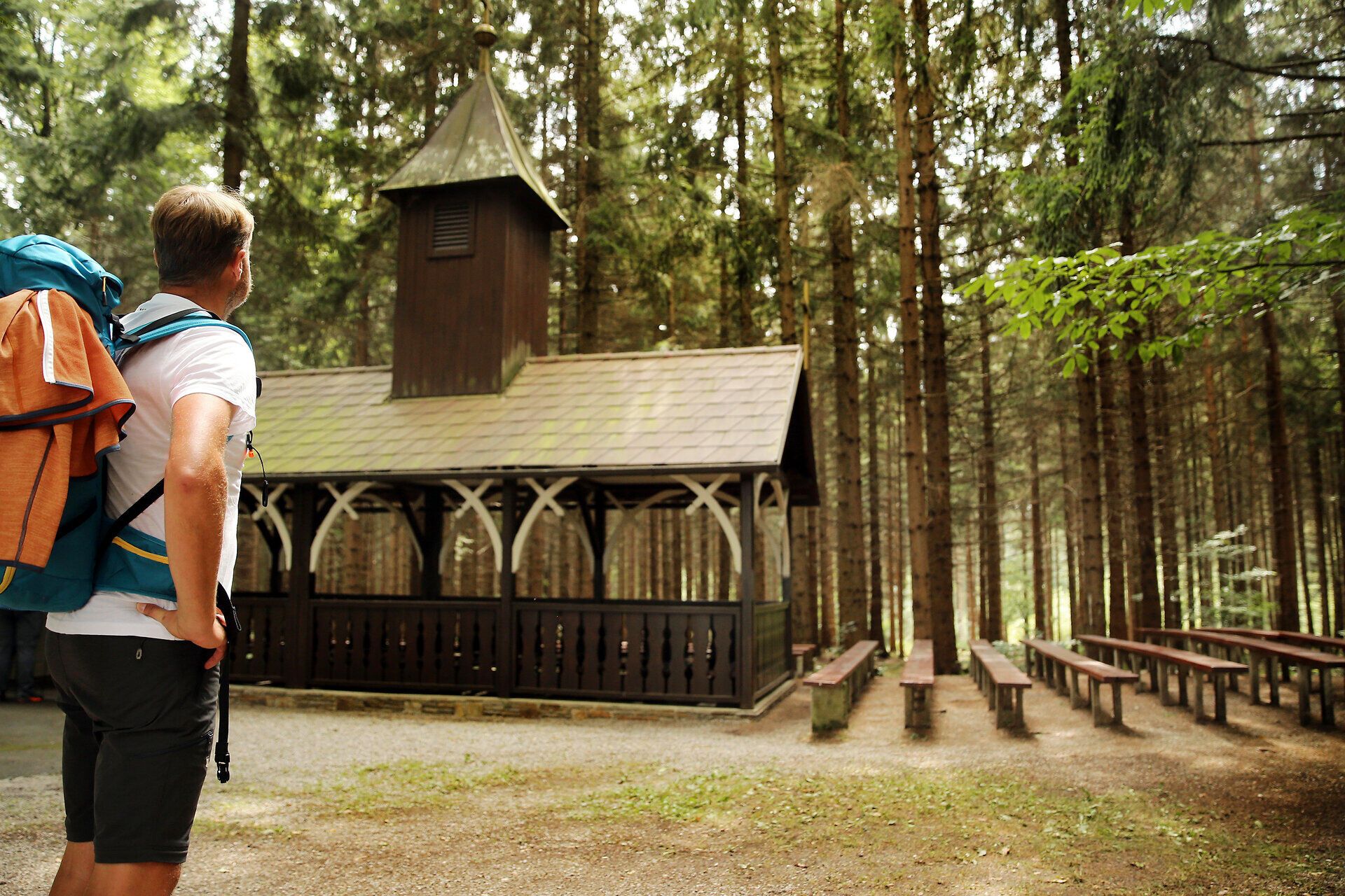 Pútnik obdivuje drevený kostol uprostred lesa.