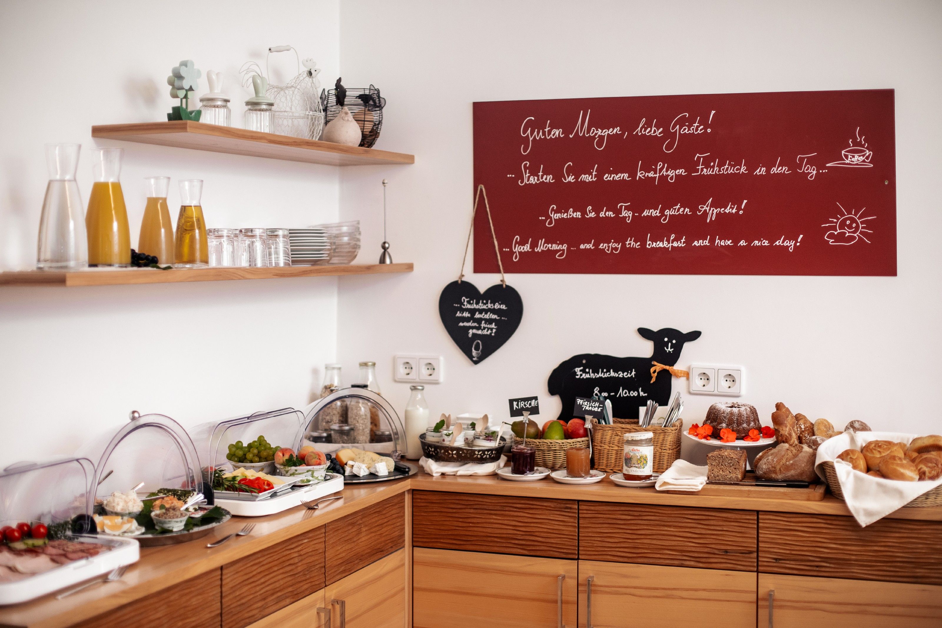 Raňajky formou bufetu s džúsom, chlebom, údeninami a ovocím v útulnej miestnosti.