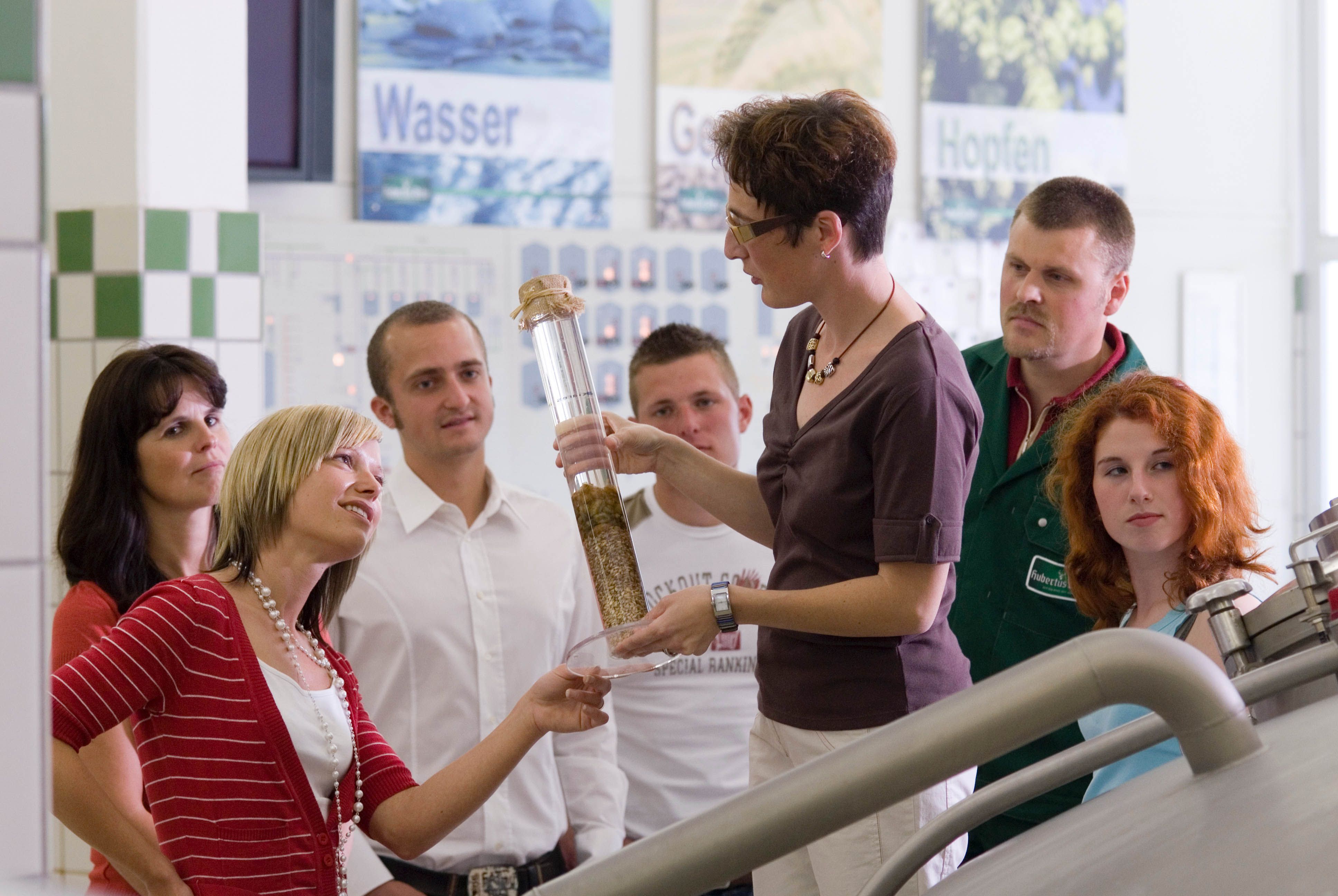 Skupina ľudí na prehliadke pivovaru so sprievodcom.