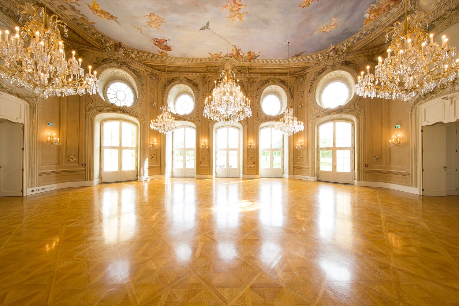 Elegantná tanečná sála s lustrami a maľovaným stropom v konferenčnom centre Laxenburg.