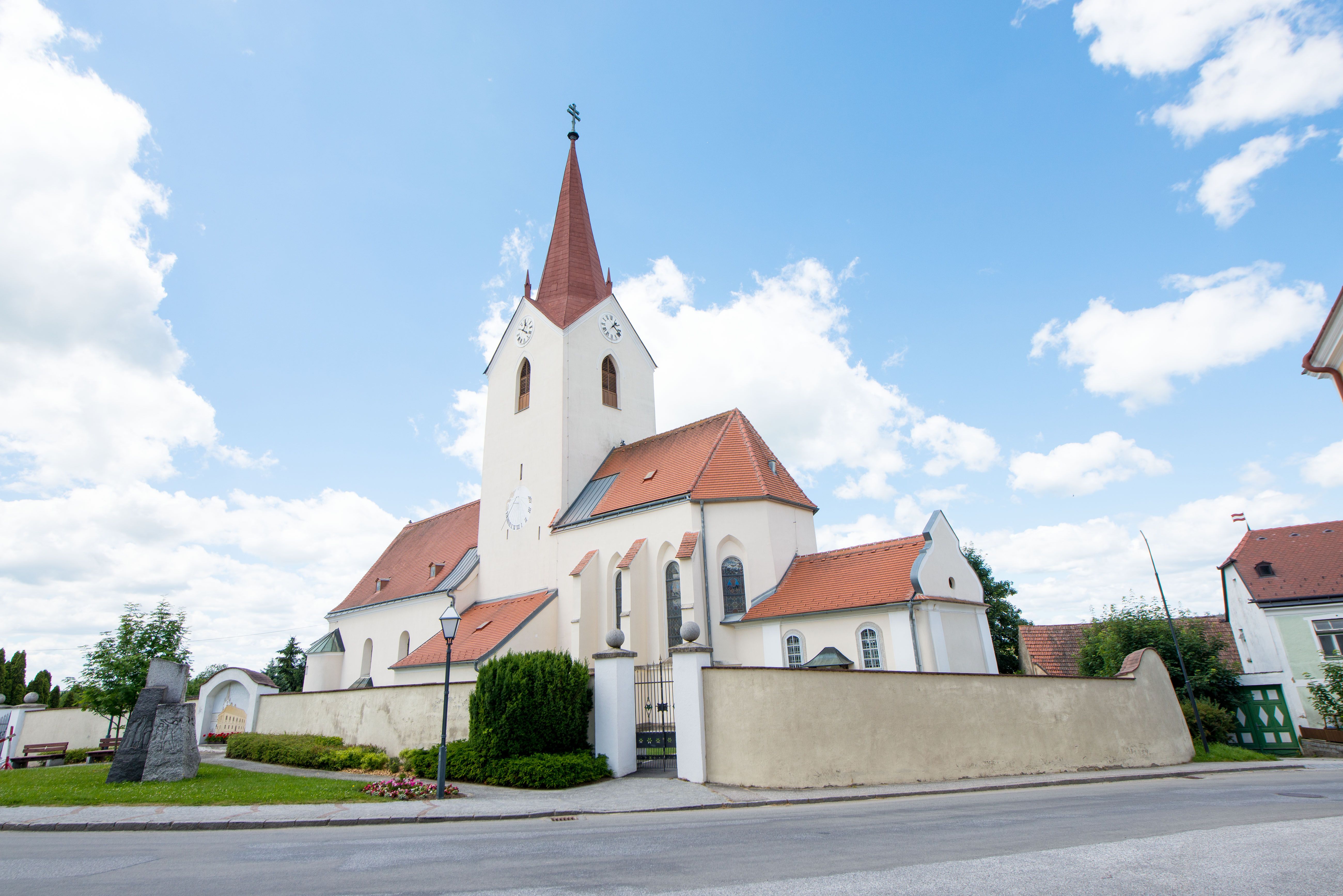 Kostol v obci Schweiggers s červenou strechou a vežou na pozadí modrej oblohy.
