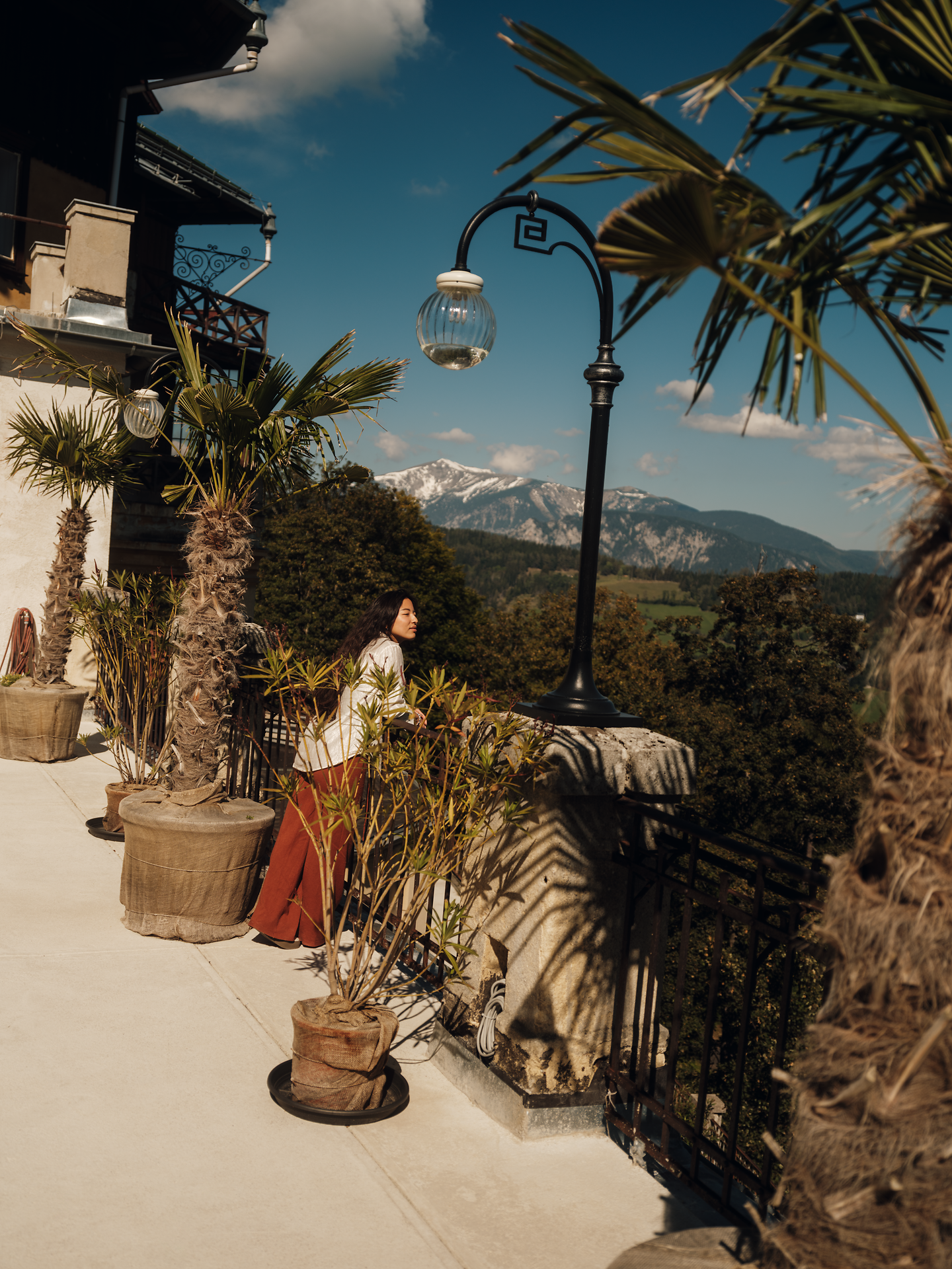 Die sanften Hügel der Wiener Alpen umarmen das Südbahnhotel Semmering, während die Sonne die Landschaft in warmes Licht taucht. Palmen und blühende Pflanzen verleihen der Terrasse einen Hauch von Exotik, während der Blick auf die majestätischen Berge zum Träumen einlädt.