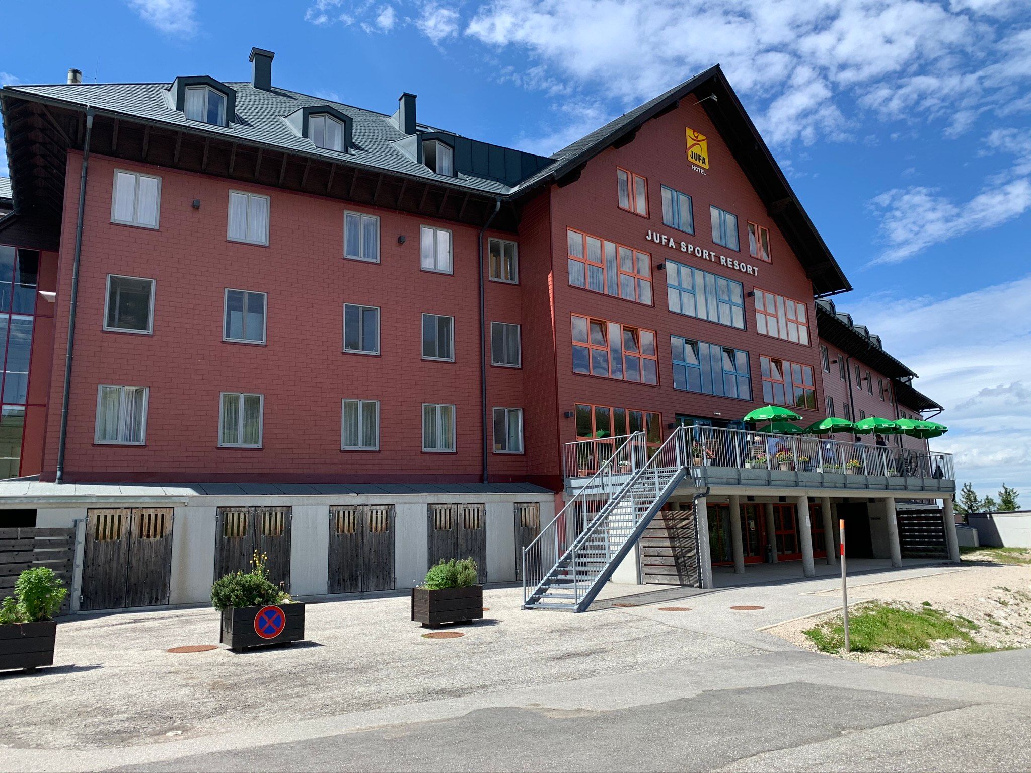 JUFA Sport Resort Hochkar s červenou fasádou a terasou so zelenými slnečníkmi.