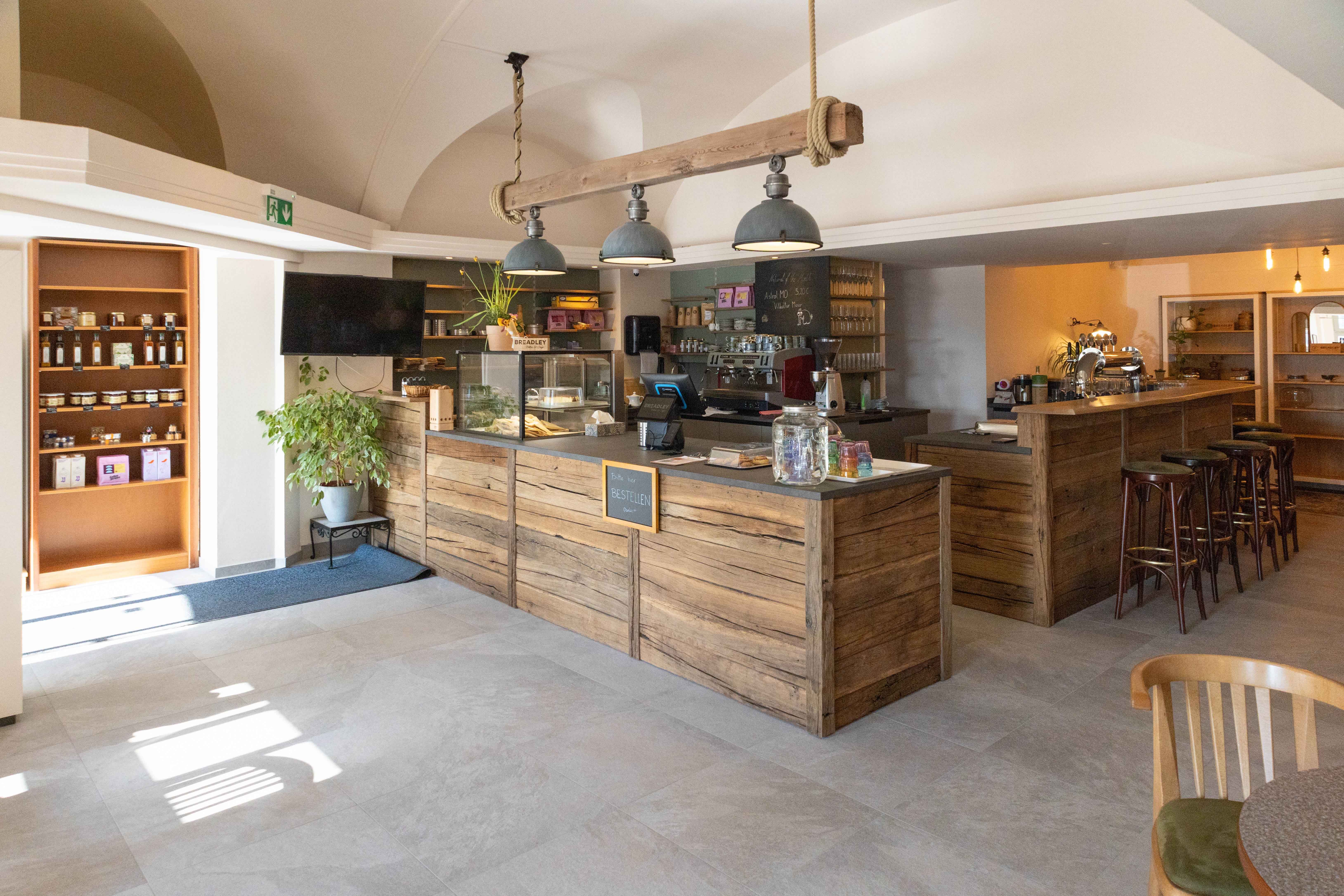 Pohľad do interiéru útulnej kaviarne s dreveným nábytkom a pultom.