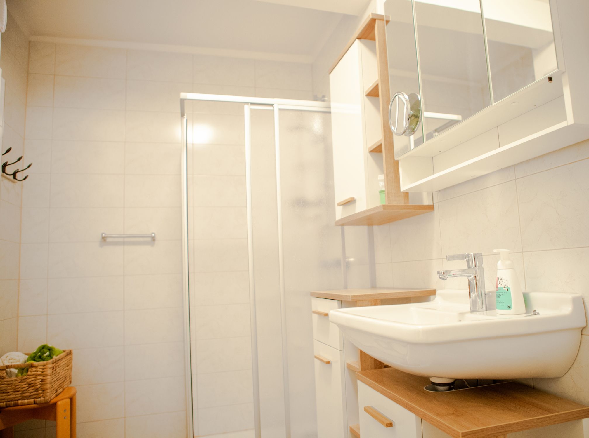 Moderná kúpeľňa so sprchovacím kútom, umývadlom a zrkadlom.