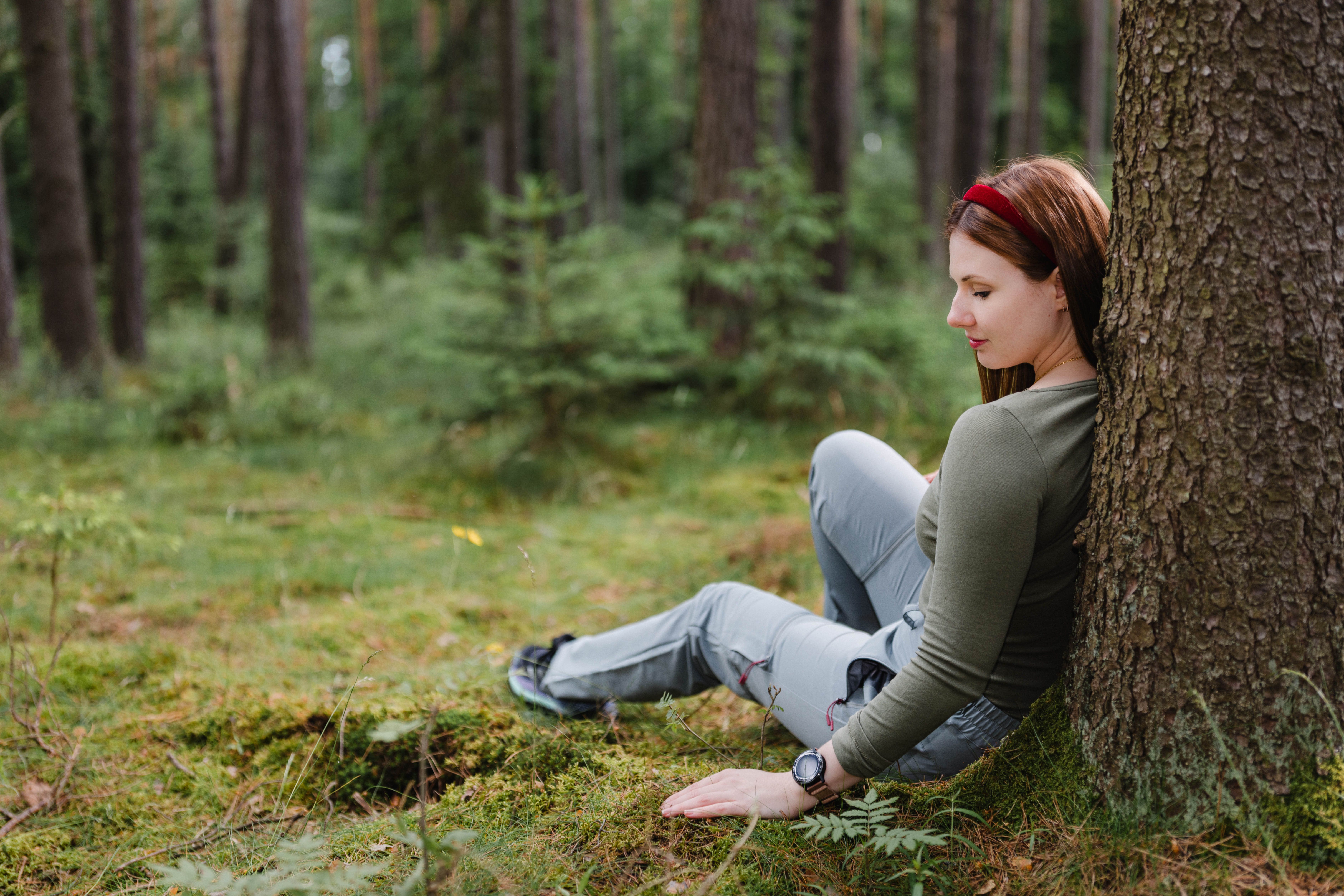 Žena opretá o strom v lese.