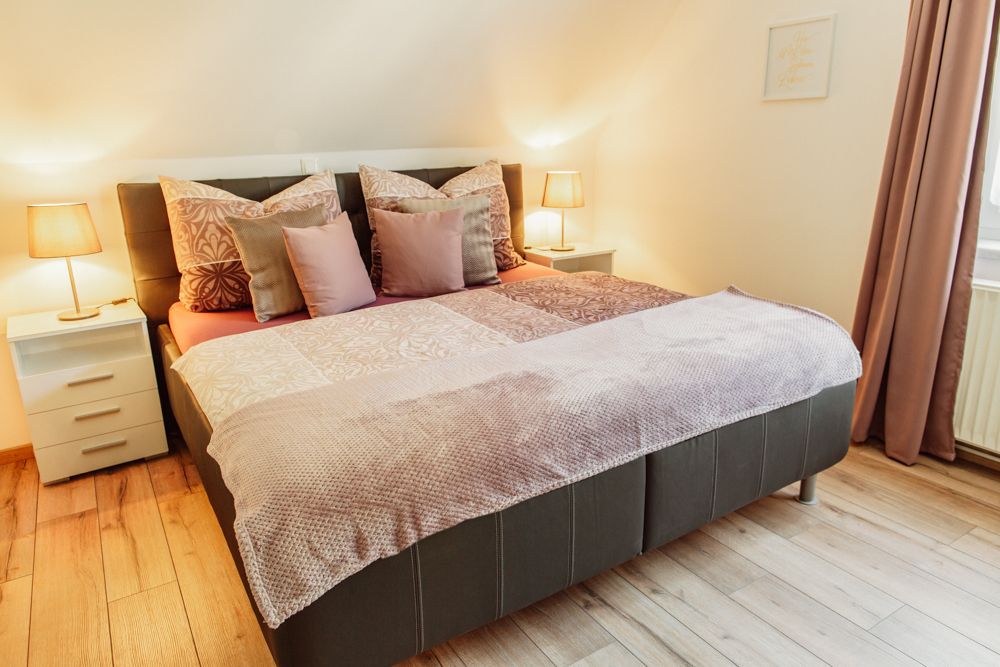 Útulná spálňa s manželskou posteľou, nočnými stolíkmi a lampami.