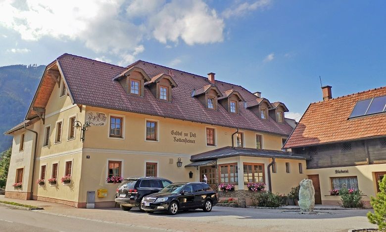 Tradičný hostinec s pekárňou a zaparkovanými autami pred ním.