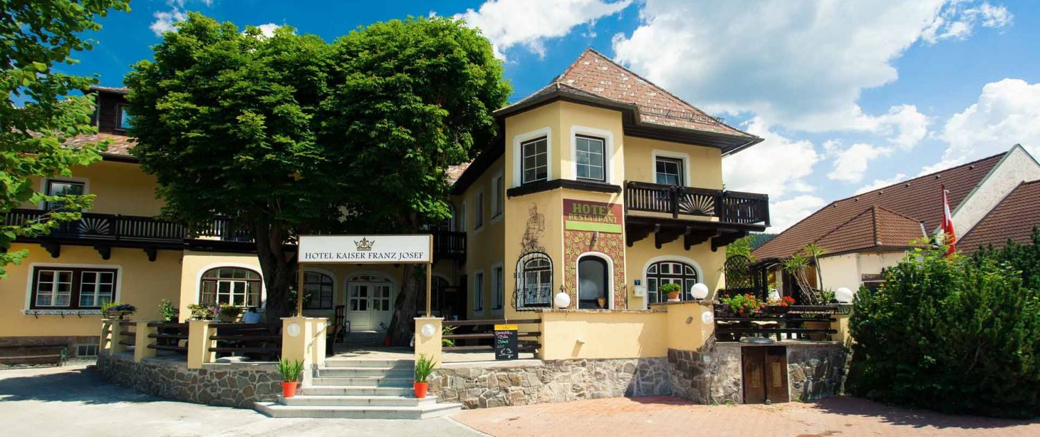Vchod do hotela Kaiser Franz Josef so žltou fasádou a balkónom.