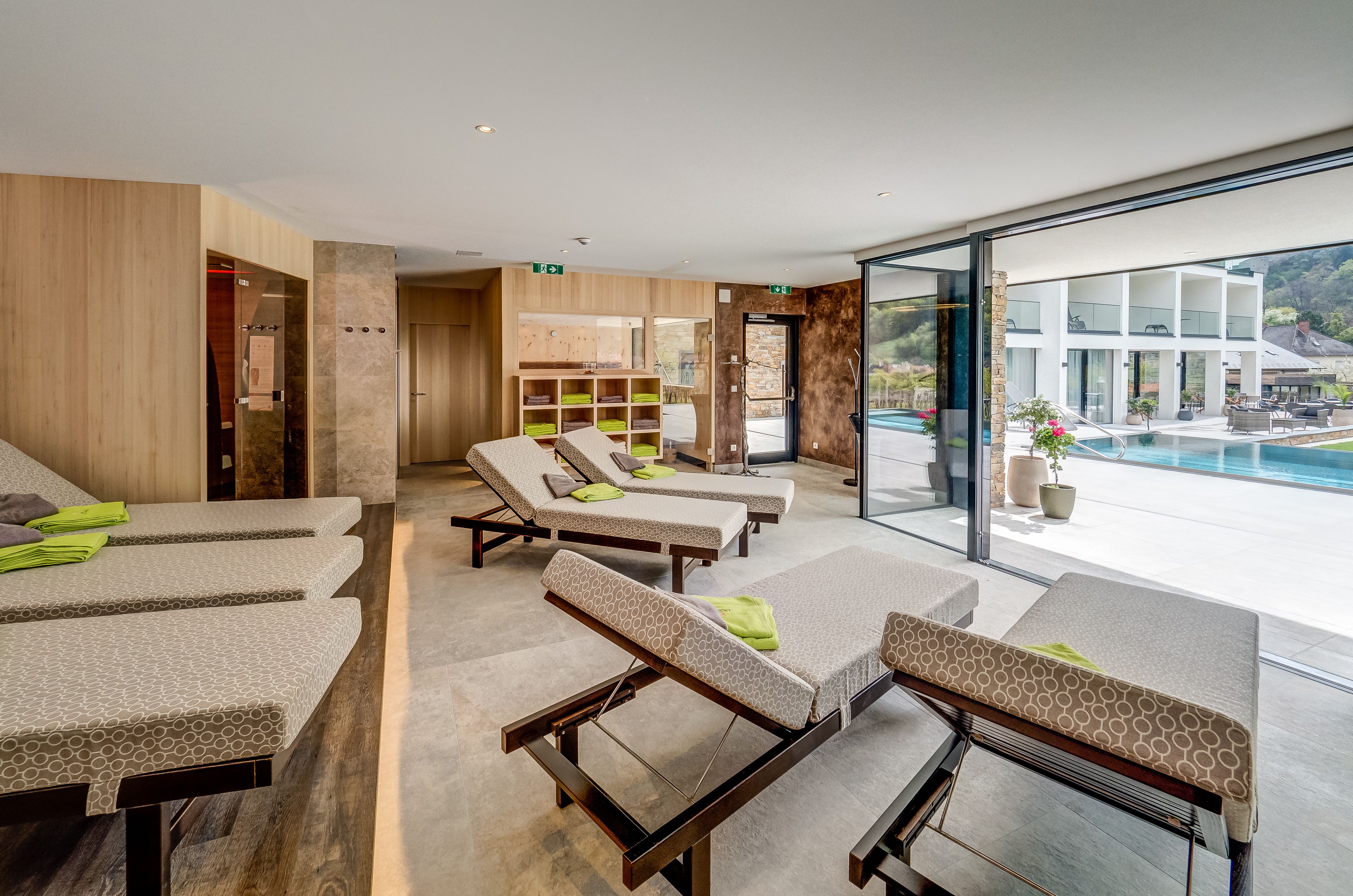 Moderná oddychová zóna s ležadlami a výhľadom na bazén cez veľké okná.