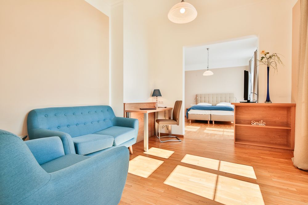 Svetlá hotelová izba s modrým nábytkom a manželskou posteľou.