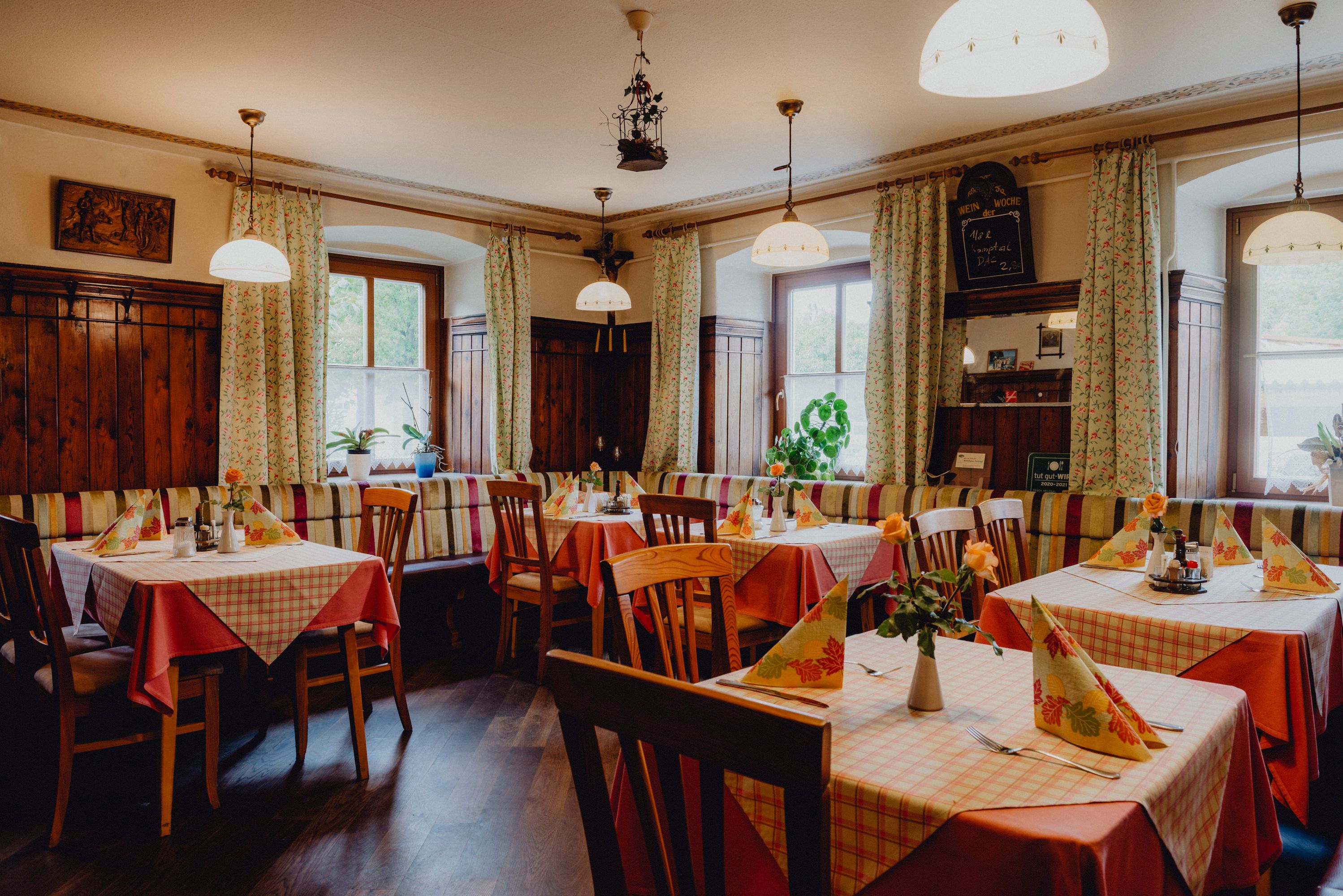 Útulný hostinec s dreveným nábytkom a károvanými obrusmi.