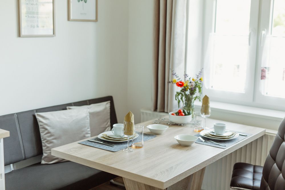 Jedálenský kút v modernom byte s prestretým stolom a kvetmi.