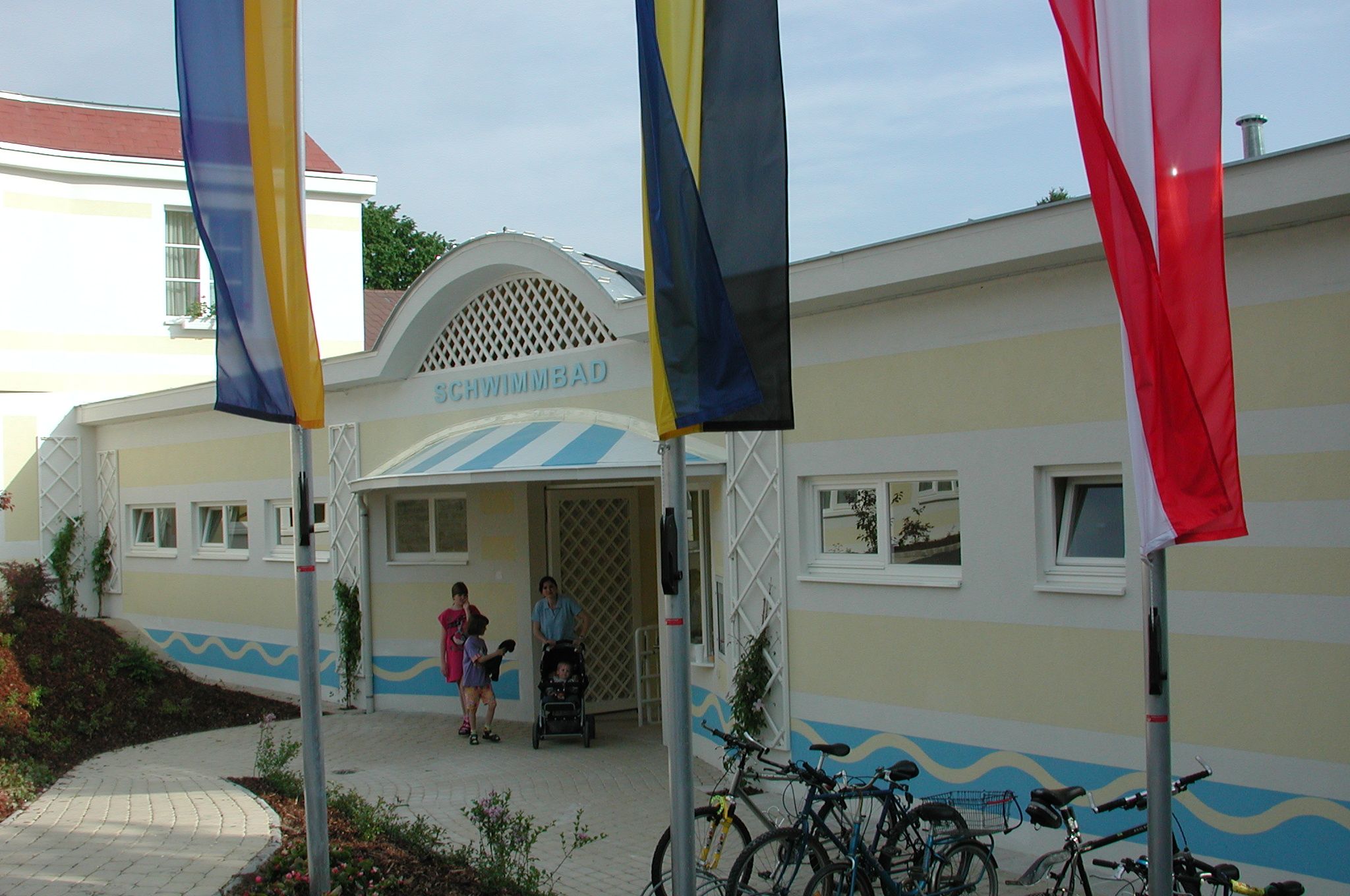 Vstup do bazéna s vlajkami a bicyklami pred ním.