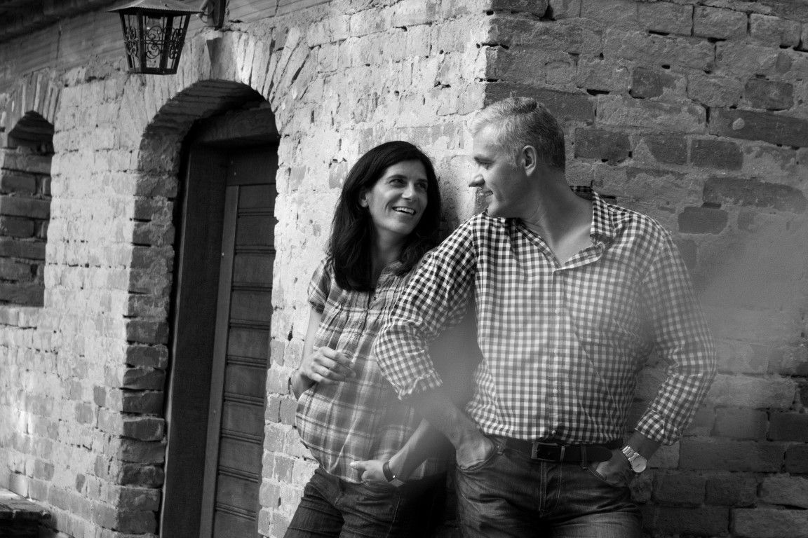 Muž a žena sa s úsmevom opierajú o tehlovú stenu.