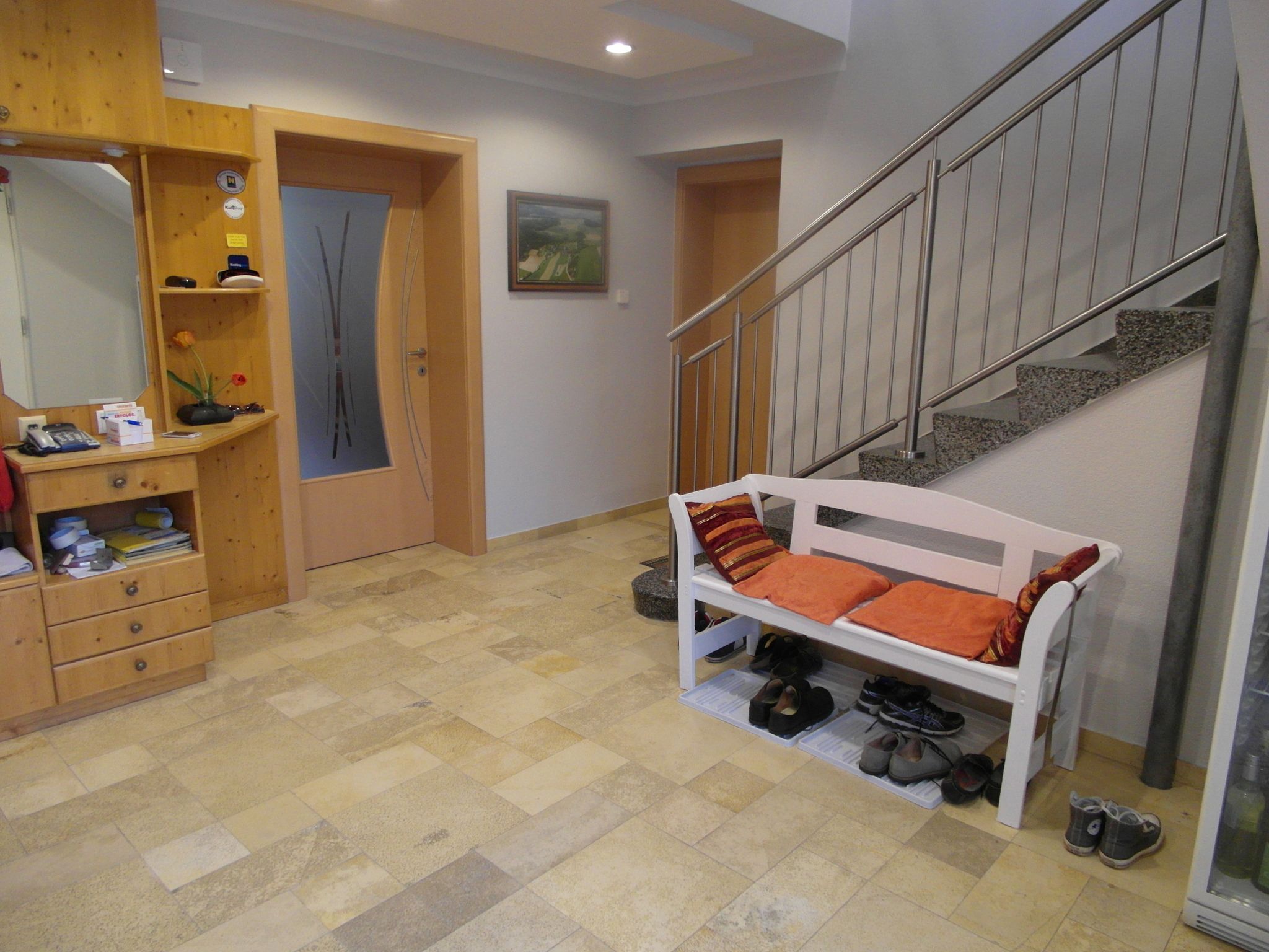 Predsieň s drevenou komodou, lavicou s vankúšmi a schodmi.