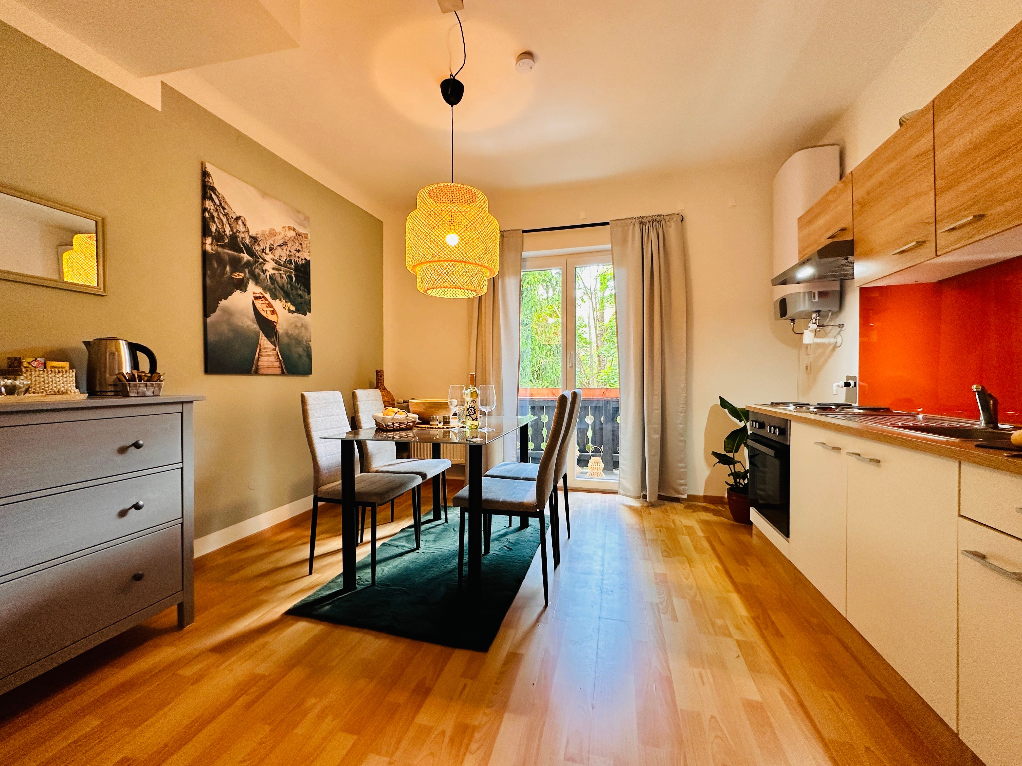 Útulný byt s jedálenským stolom, stoličkami, kuchynským kútom a balkónom.