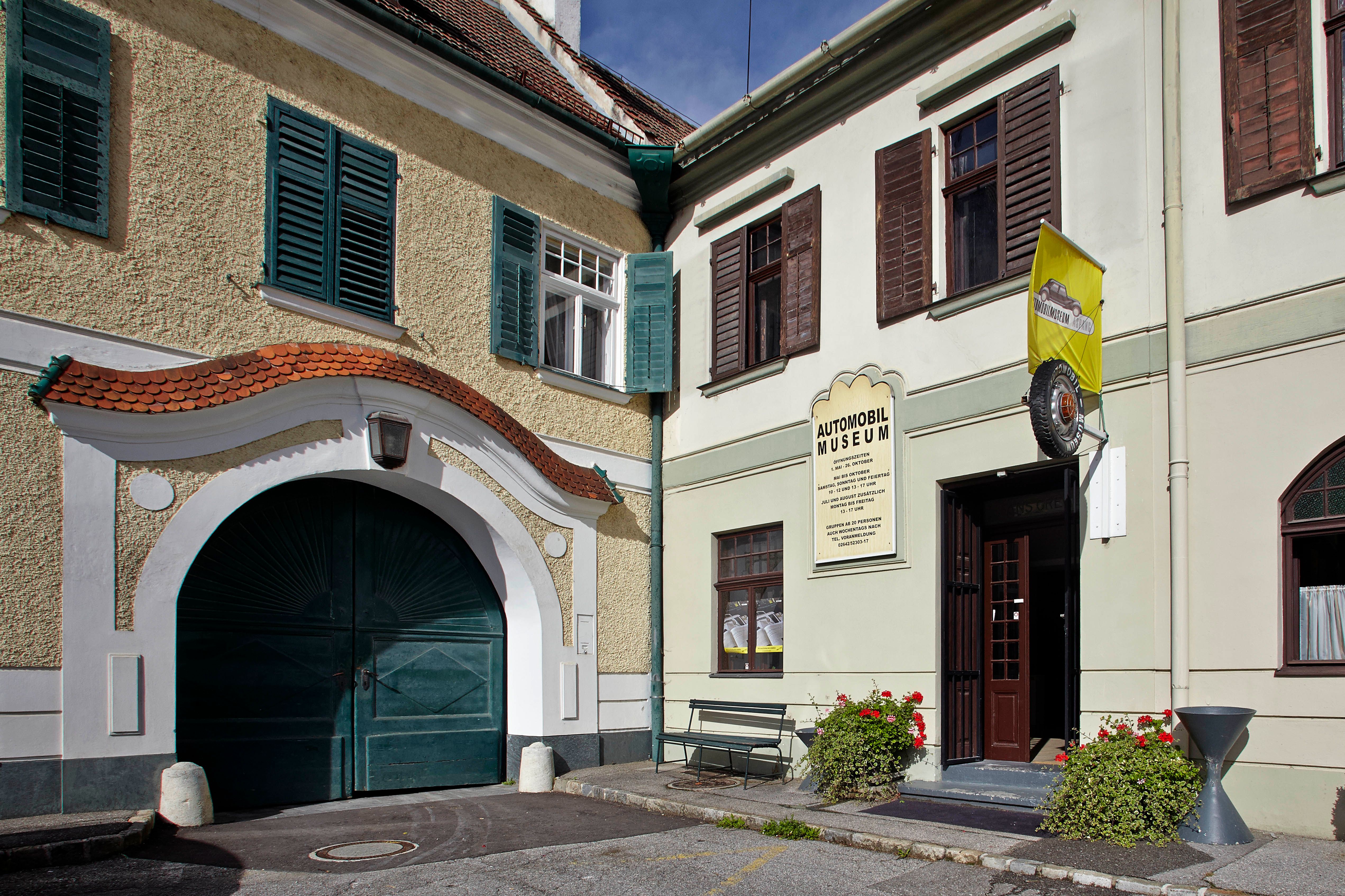 Vchod do múzea automobilov Aspang Market so žltou vlajkou a kvetmi.