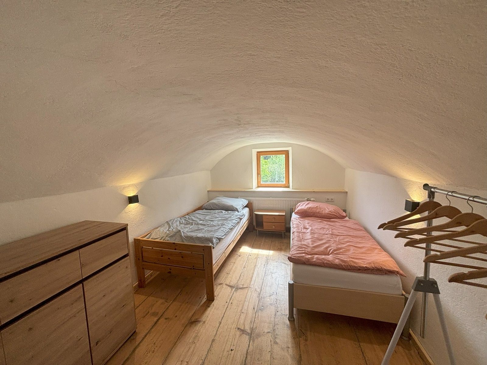 Jednoduchá dvojlôžková izba s dvoma samostatnými posteľami, komodou a vešiakom na oblečenie. Malé okno prepúšťa prirodzené svetlo.