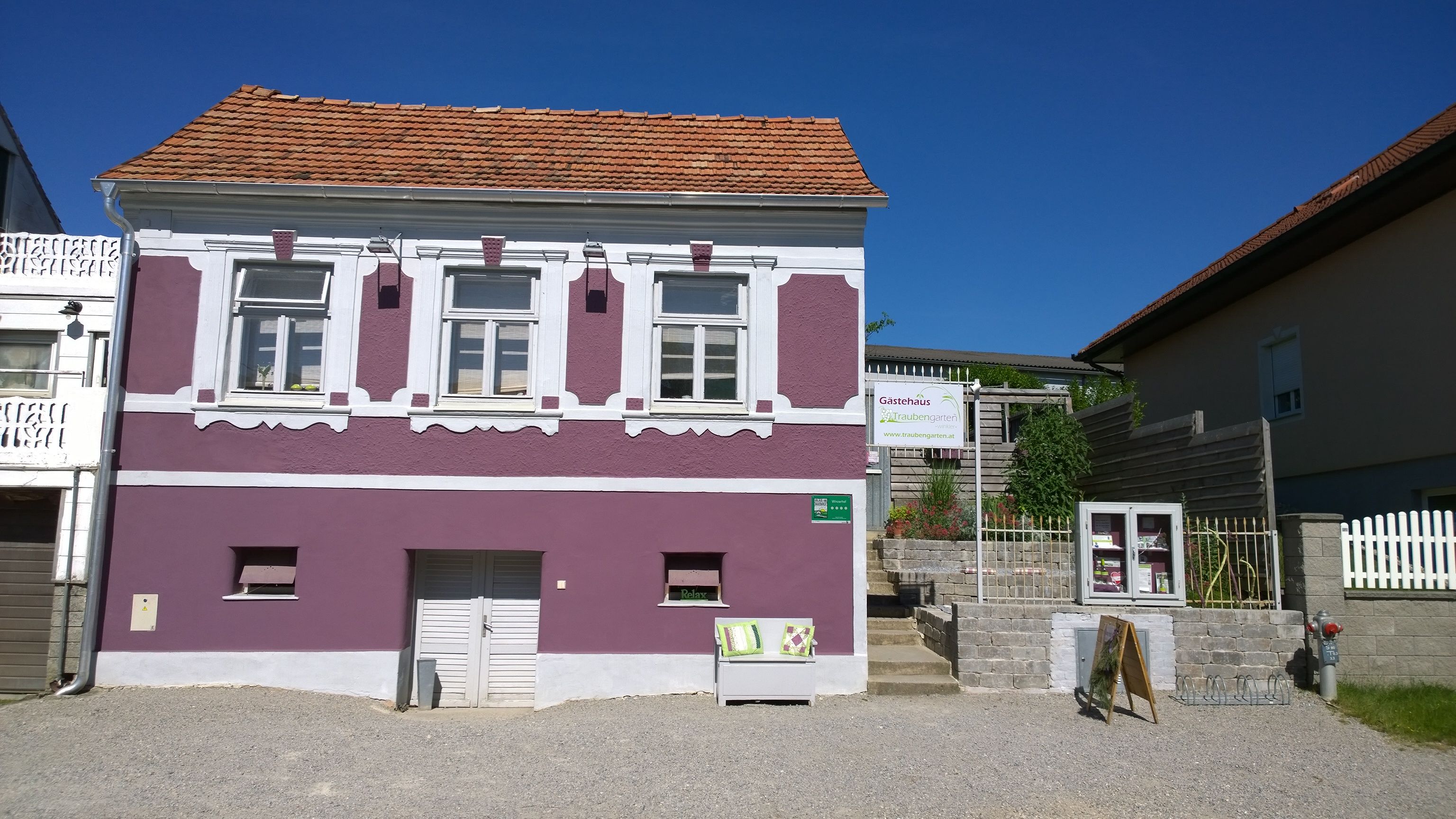 Exteriérový pohľad na fialový dom s bielymi okennými rámami a nápisom penzión.