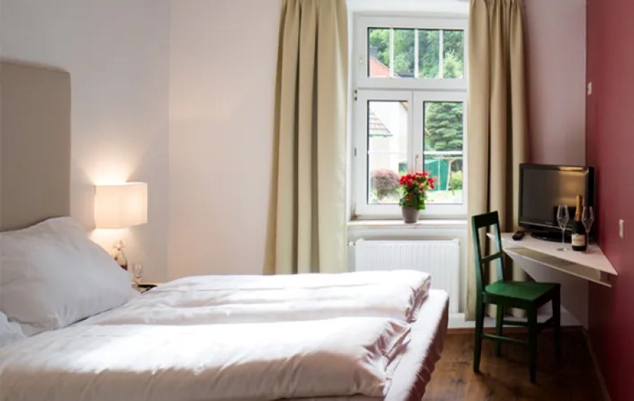 Manželská posteľ s oknom a rohovým stolíkom s TV