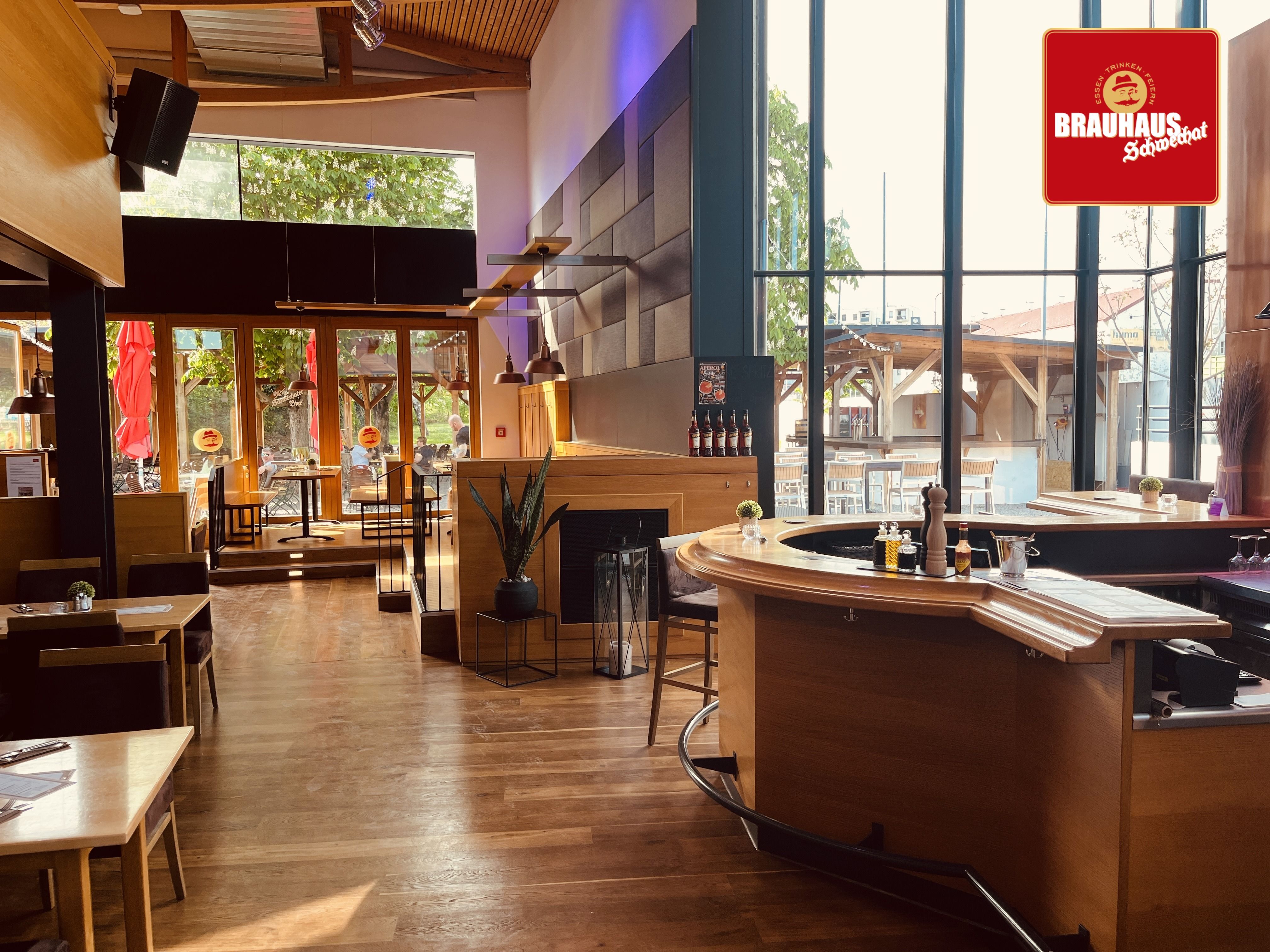 Pohľad do interiéru moderného pivovaru s dreveným nábytkom a veľkými oknami.