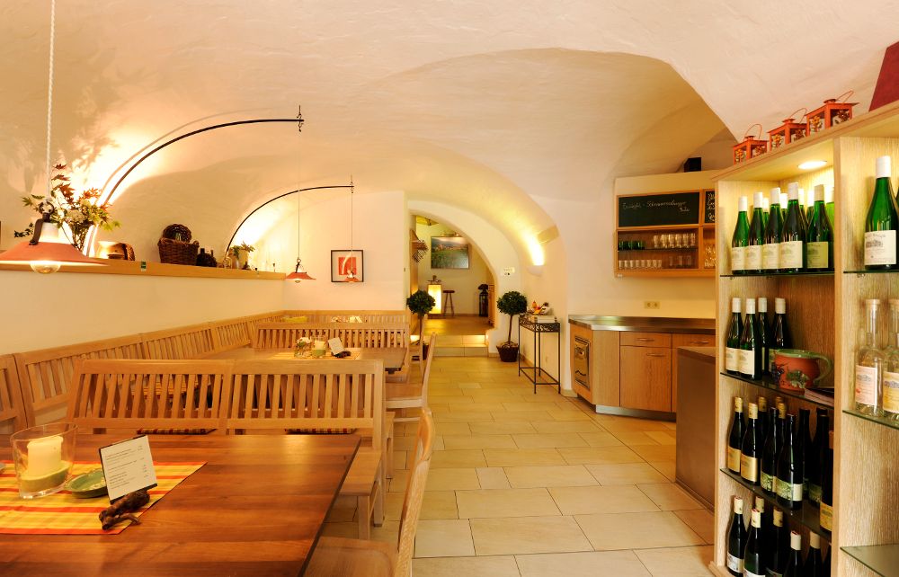 Pohľad do interiéru útulnej vinárne s drevenými stolmi a stojanmi na víno.